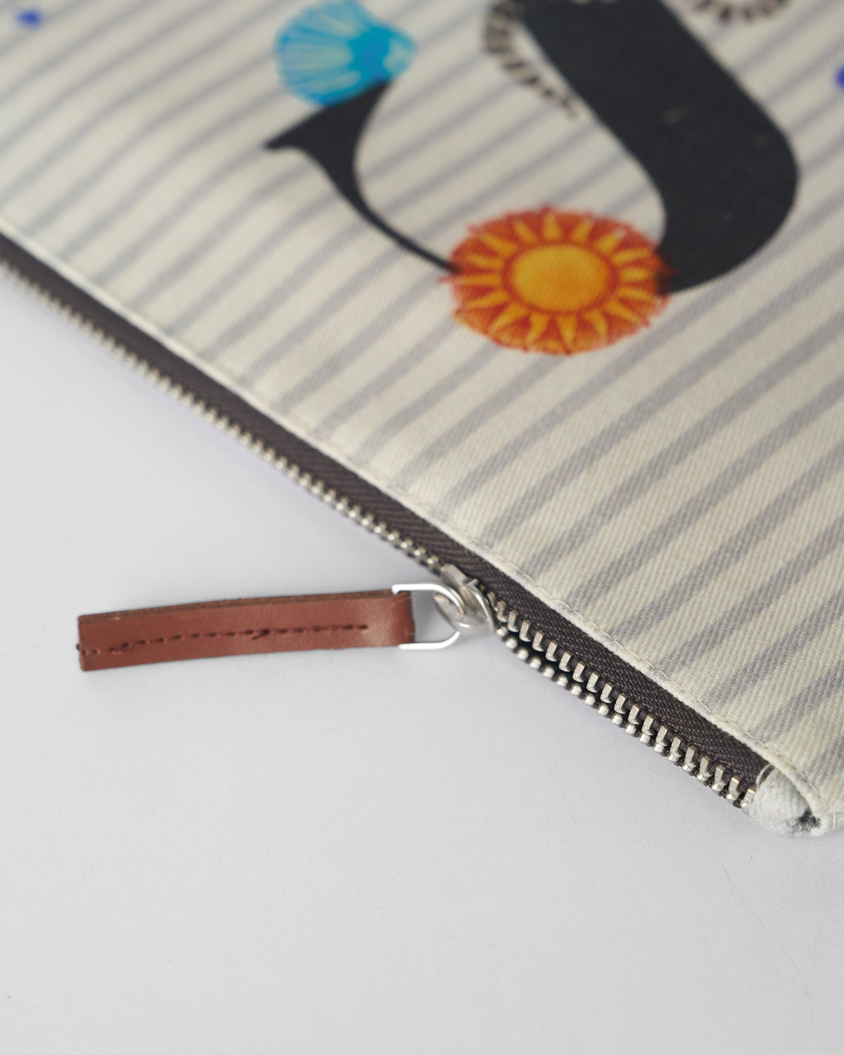 Close-up of the Sitara Pouch zipper with a brown leather pull tab.
