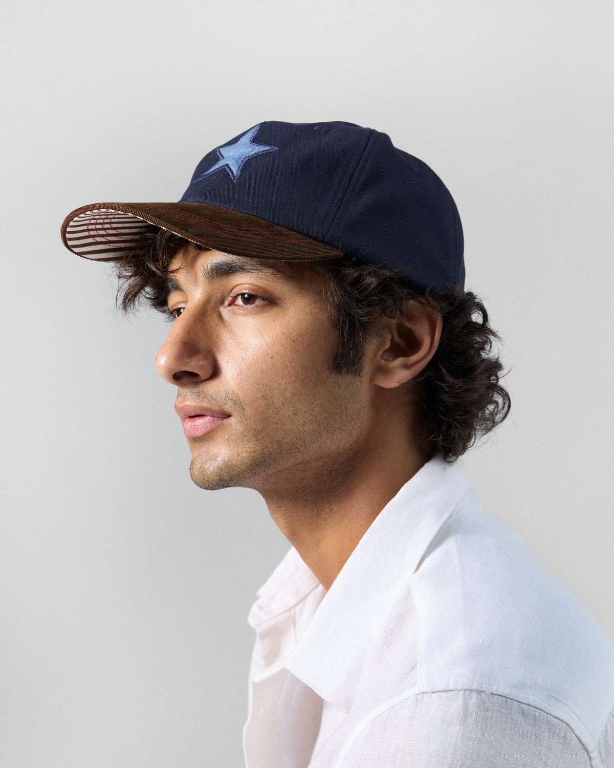 Side profile of a person wearing a navy Starry Cap with a brown brim.