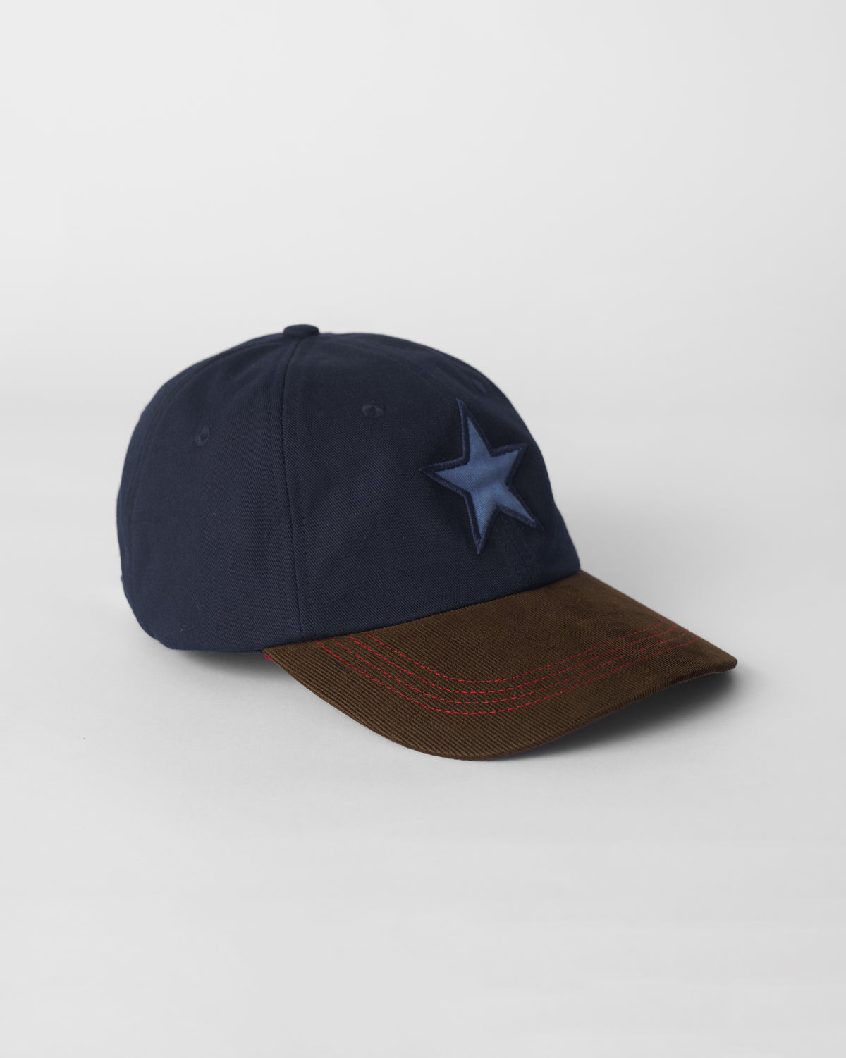 Three-quarter view of a navy and brown Starry Cap with a blue star.