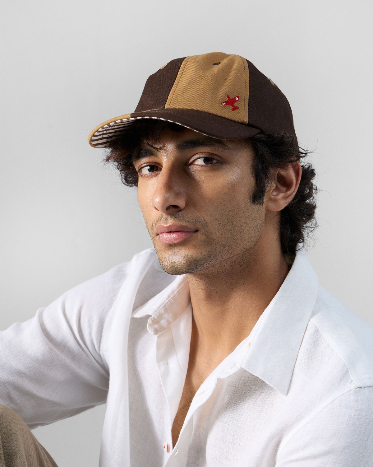 Person wearing a brown and beige Aero Cap with a red airplane motif.