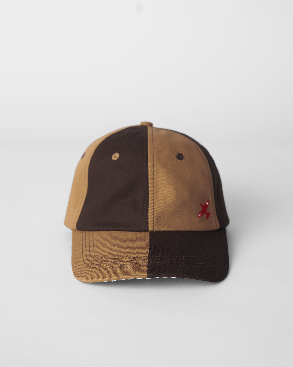 Front of a brown and beige Aero Cap with a red airplane embroidery.