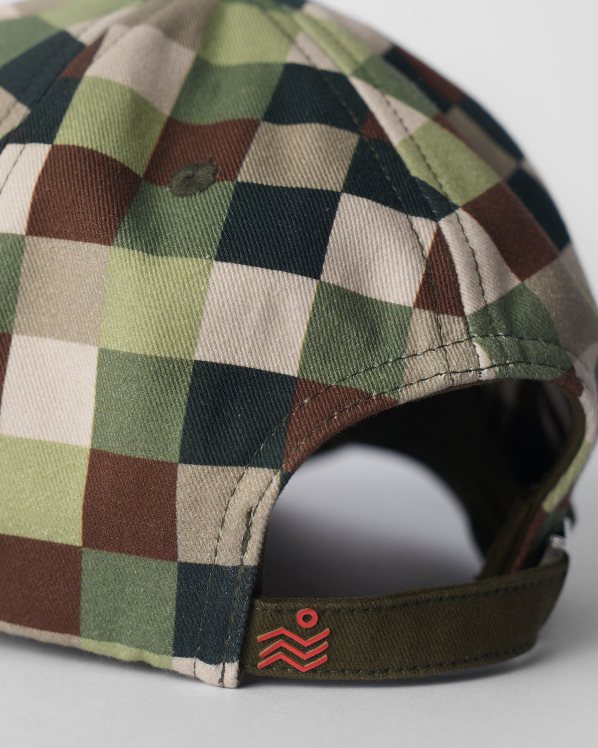 Back of an olive pixel-print cap with an adjustable strap and red Nicobar mark.