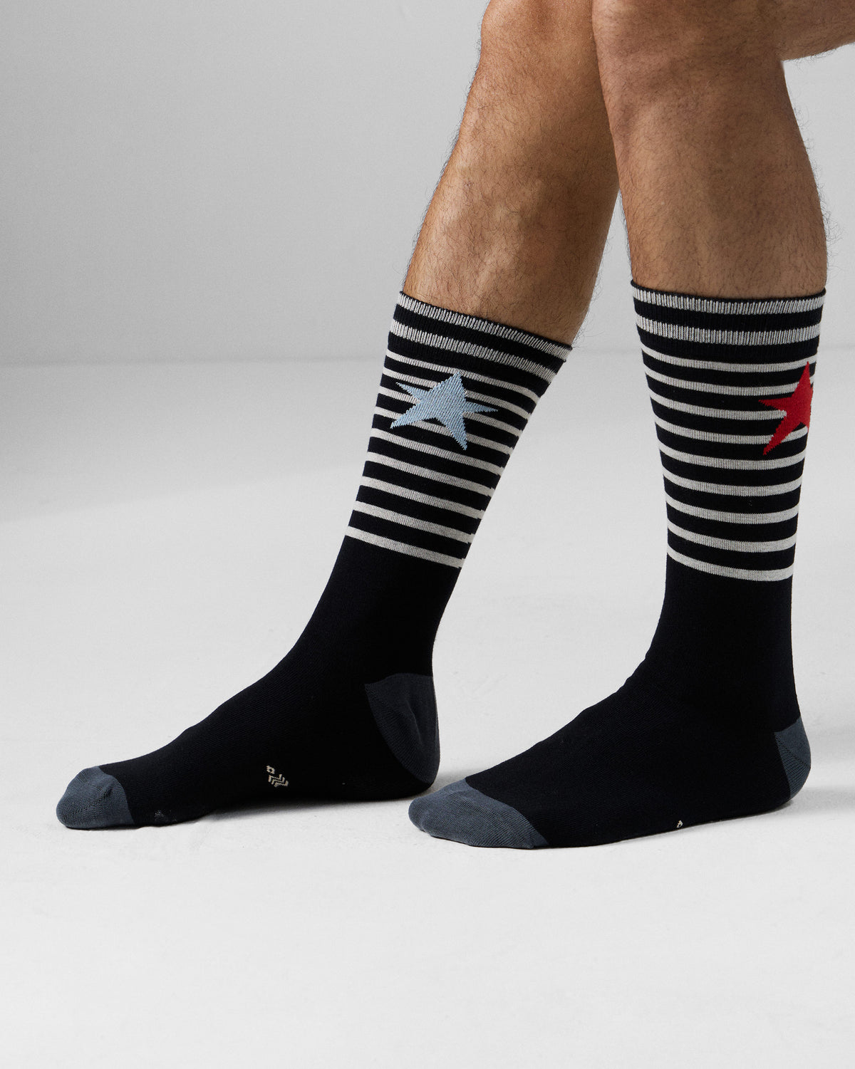 Black Starfly socks worn mid-calf, showing striped cuffs and mismatched stars.