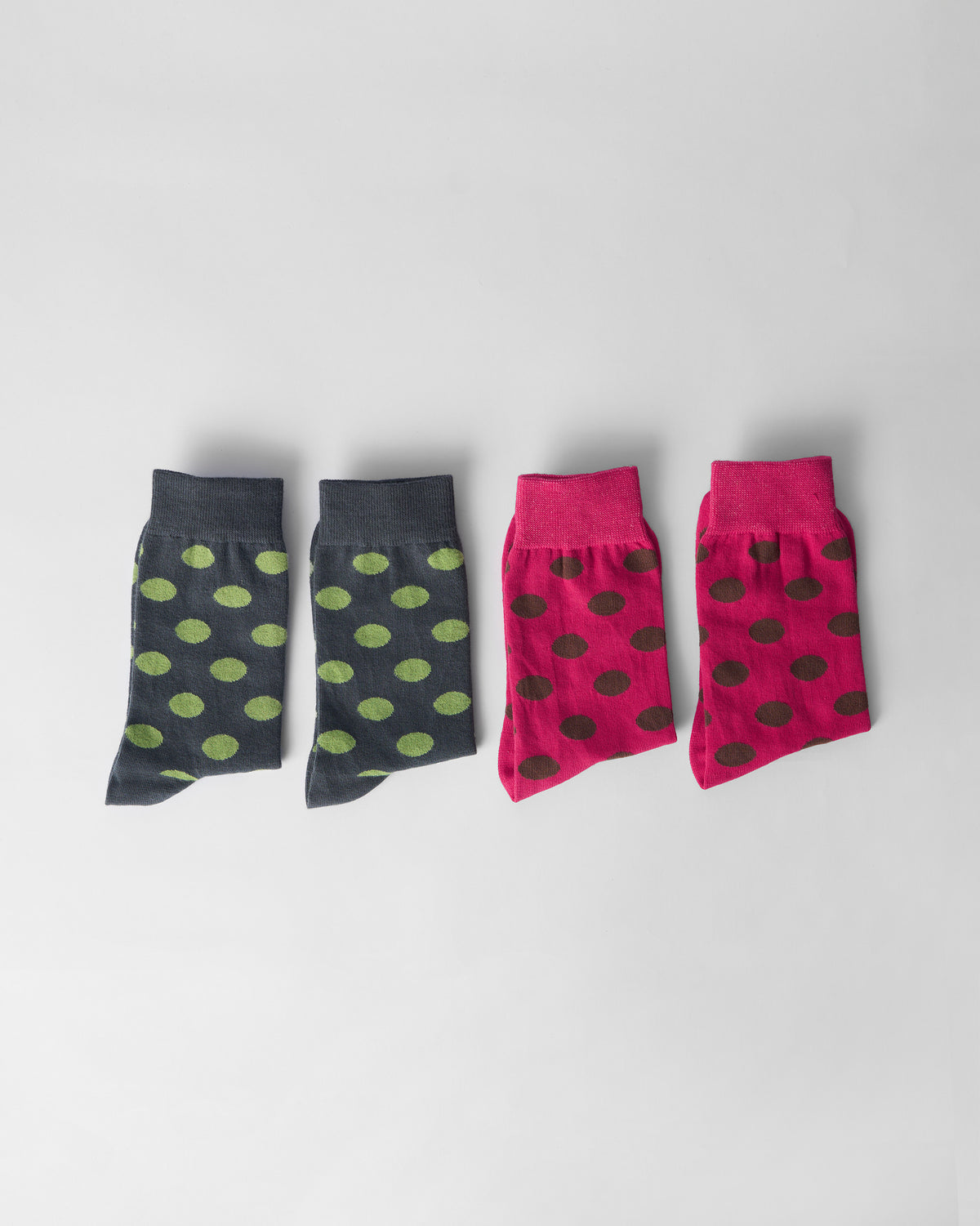 Fuchsia and charcoal Polka Love socks laid flat in a row.