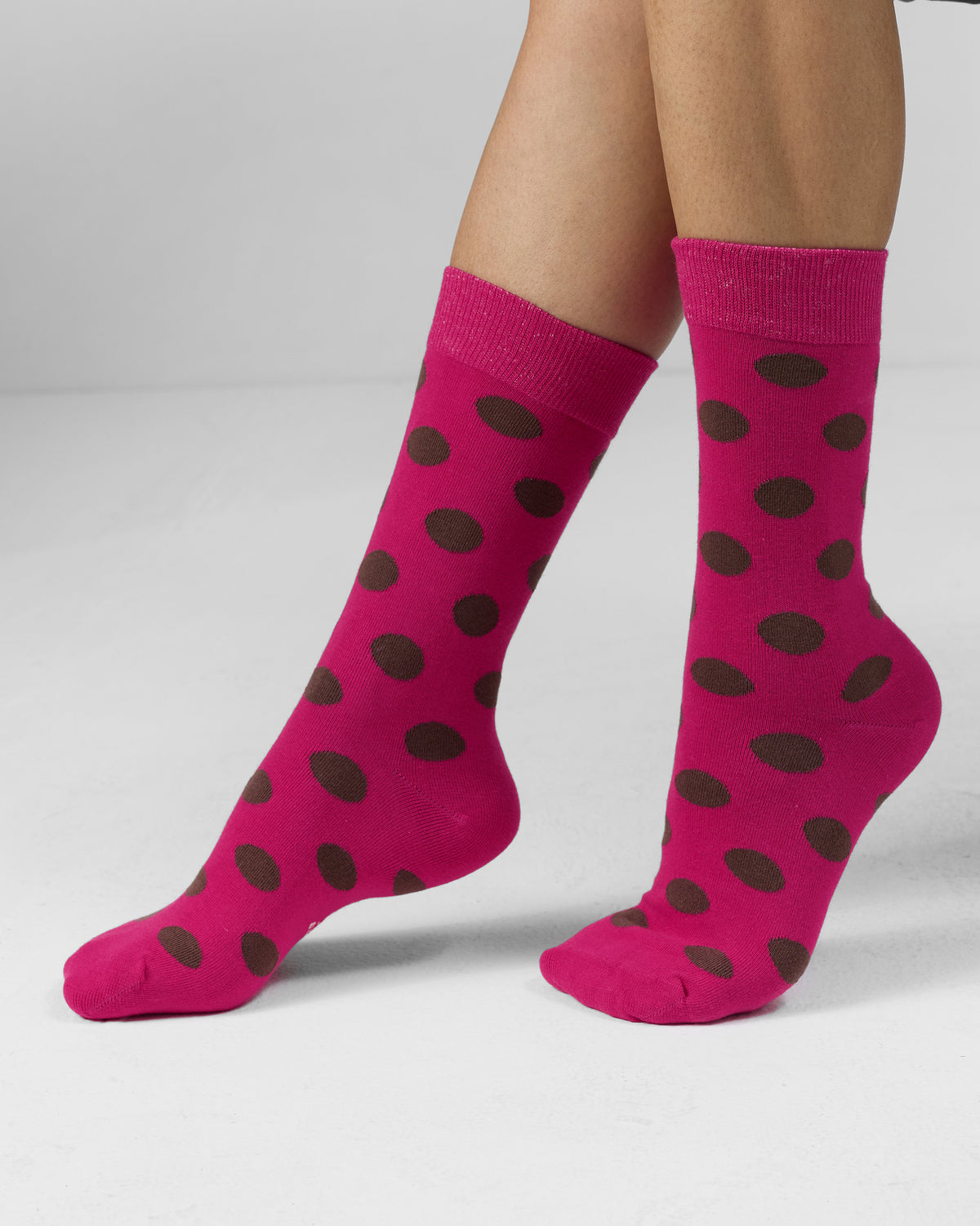 Fuchsia Polka Love socks with brown polka dots worn on feet.