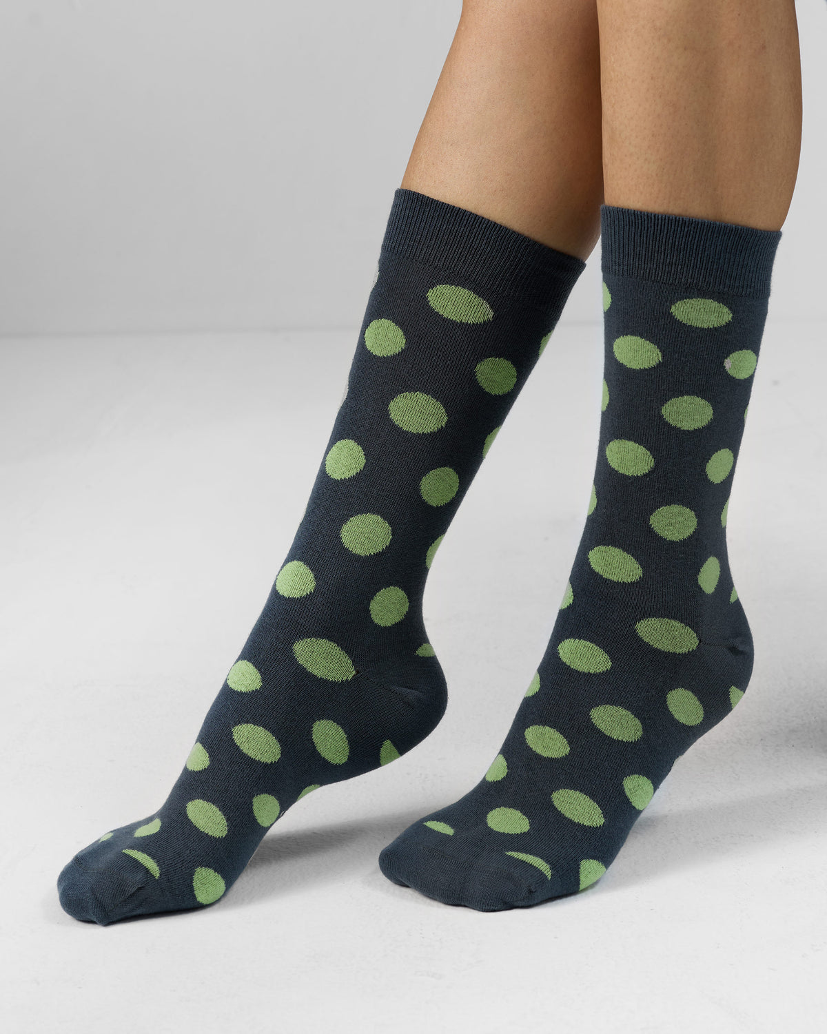 Charcoal Polka Love socks with green polka dots worn on feet.