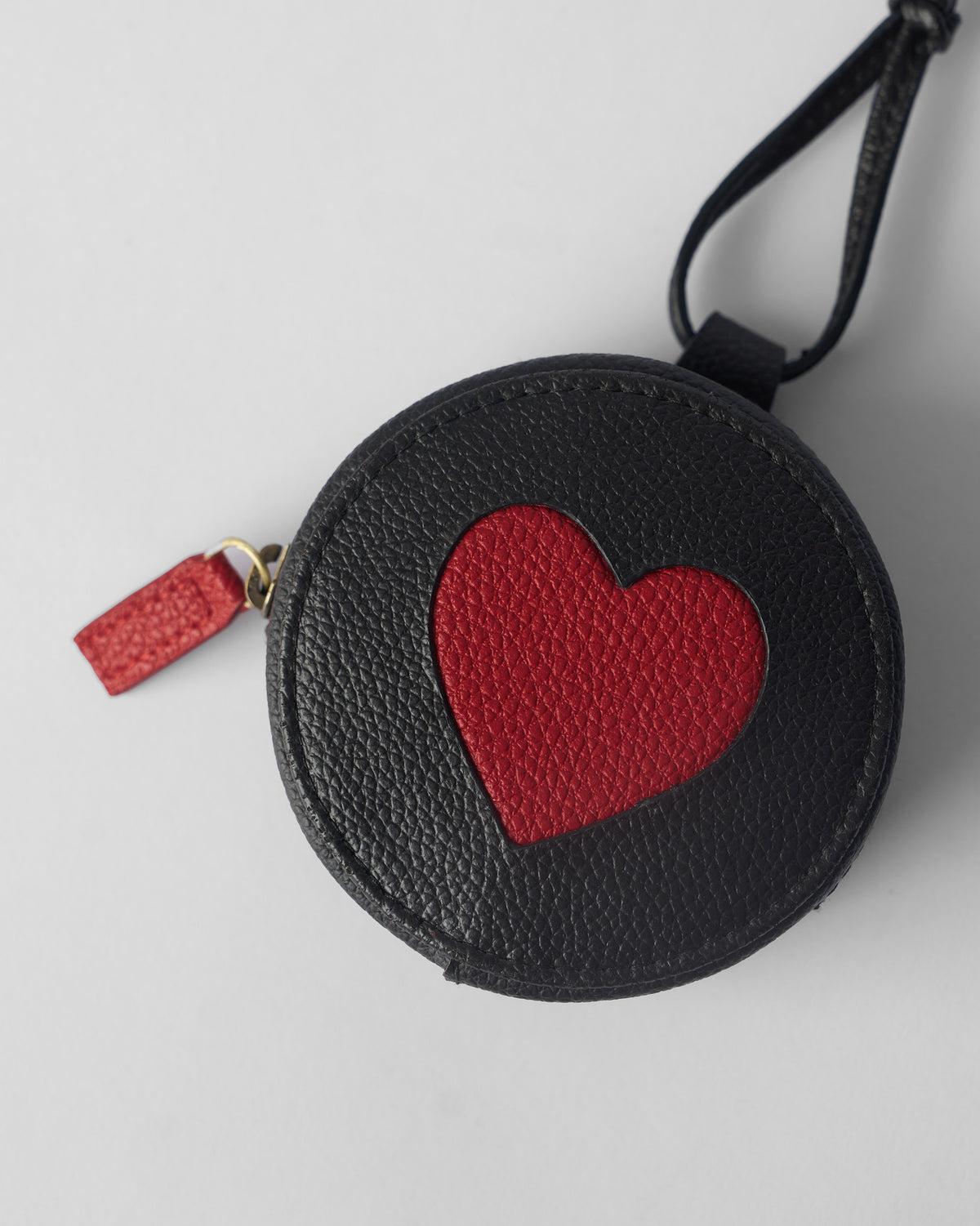 Back of a black Nova Charm showing a red heart and red zipper pull.