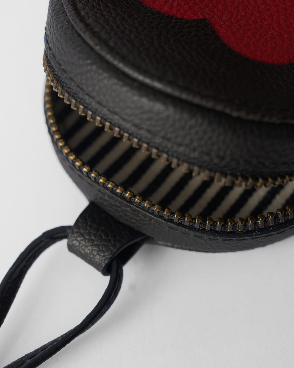 Close-up of a black Nova Charm unzipped to show a striped lining.