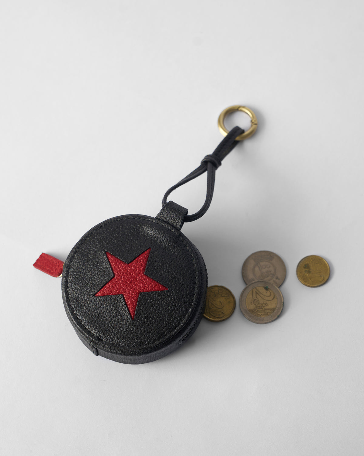 Black Nova Charm with a red star beside coins for scale.