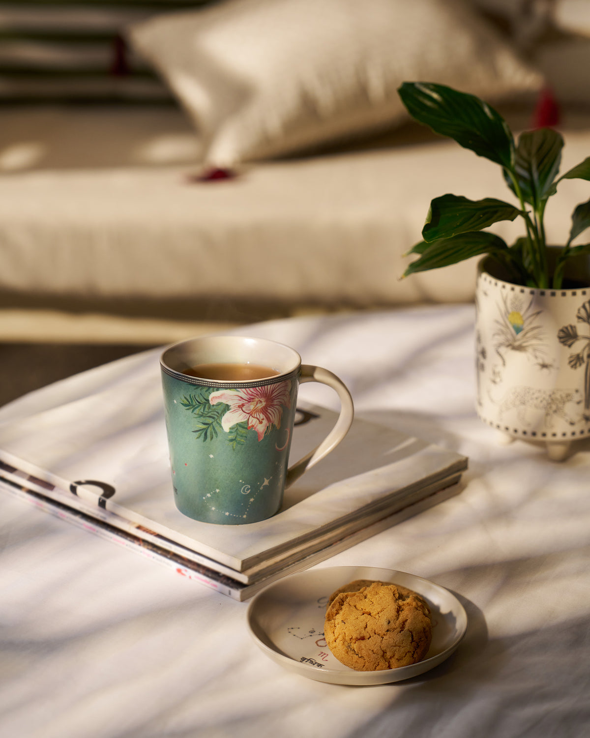 Nico Scorpio mug and tea plate with cookies in a sunlit setting.