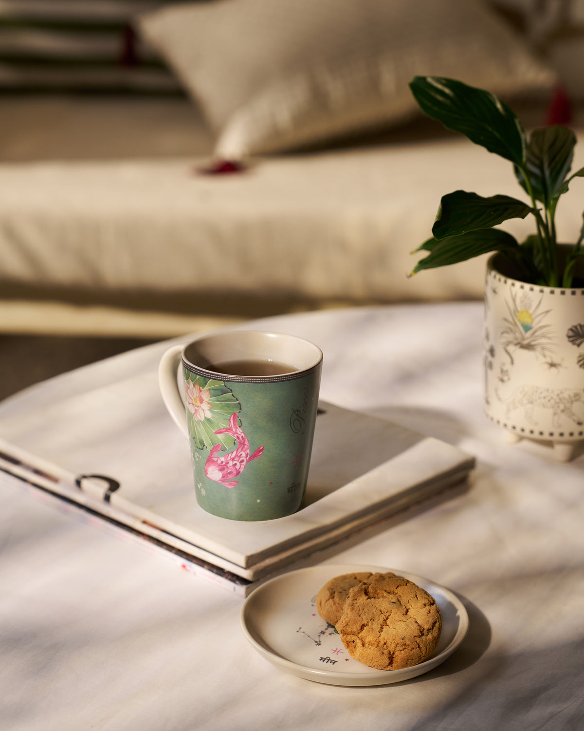 Nico Pisces Gift Set mug of tea on a tray, with a biscuit on the saucer.