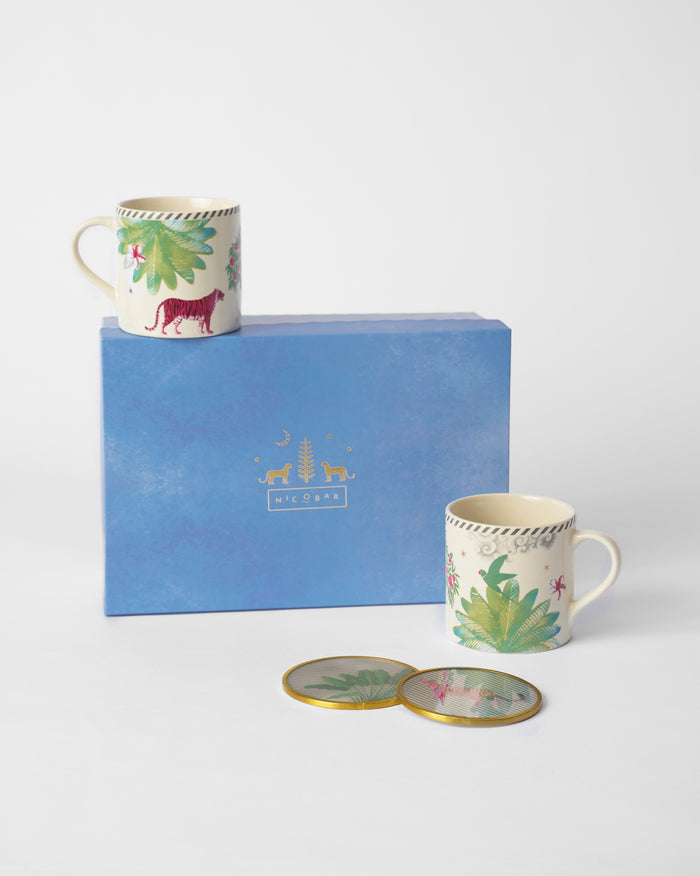Two Ceylon Lush mugs with palm and animal motifs beside a blue gift box and coasters.
