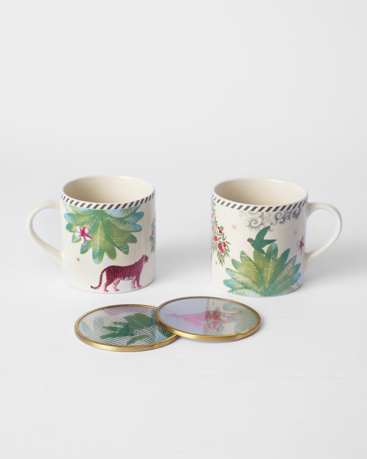 Two Ceylon Lush mugs with palm motifs and coasters, seen from a lower angle.