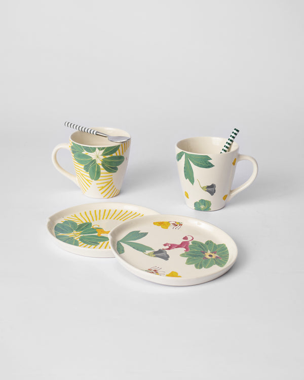 Two mug and plate pairs set out with striped spoons