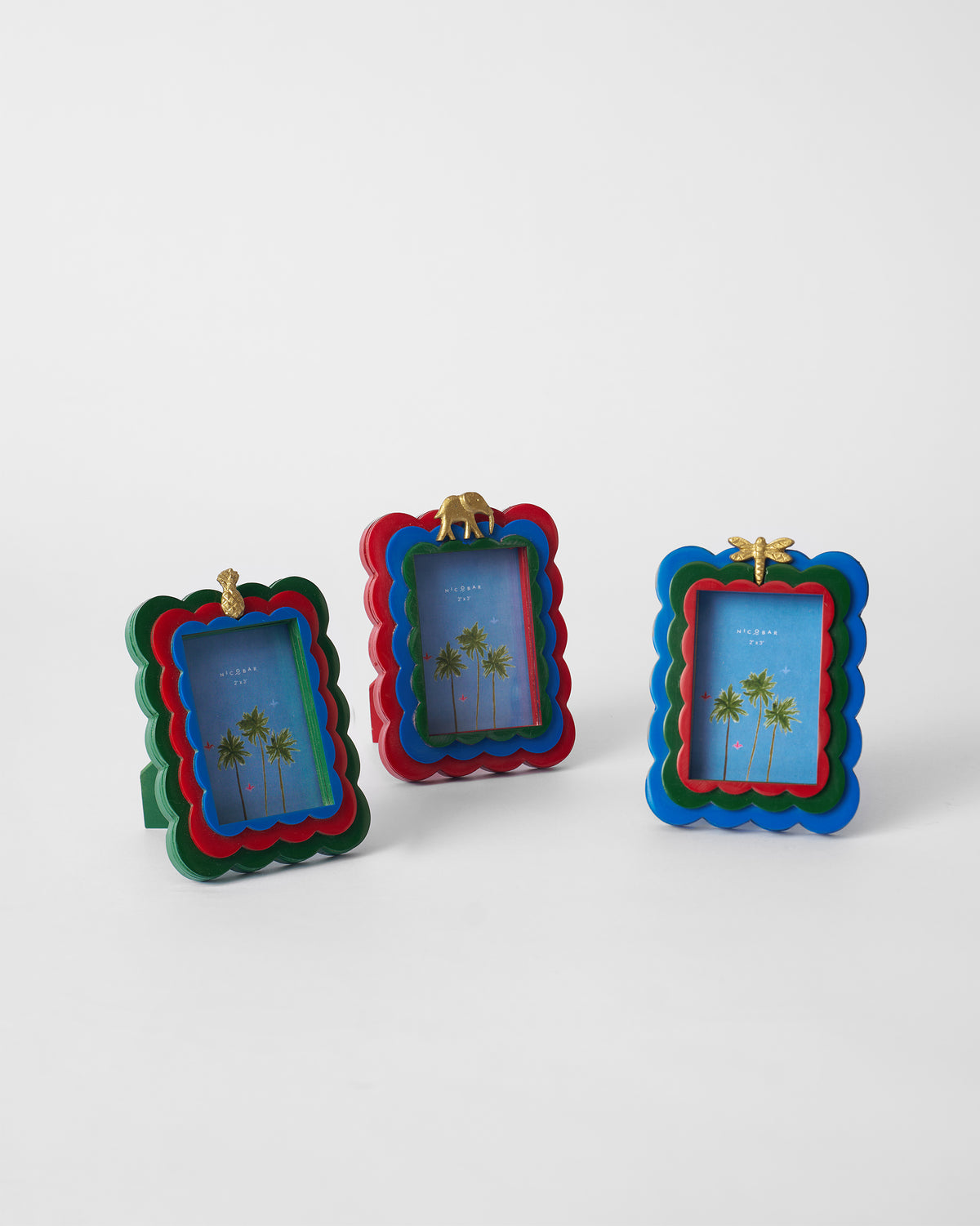 Three Tropics scalloped photo frames with gold pineapple, elephant, and dragonfly.