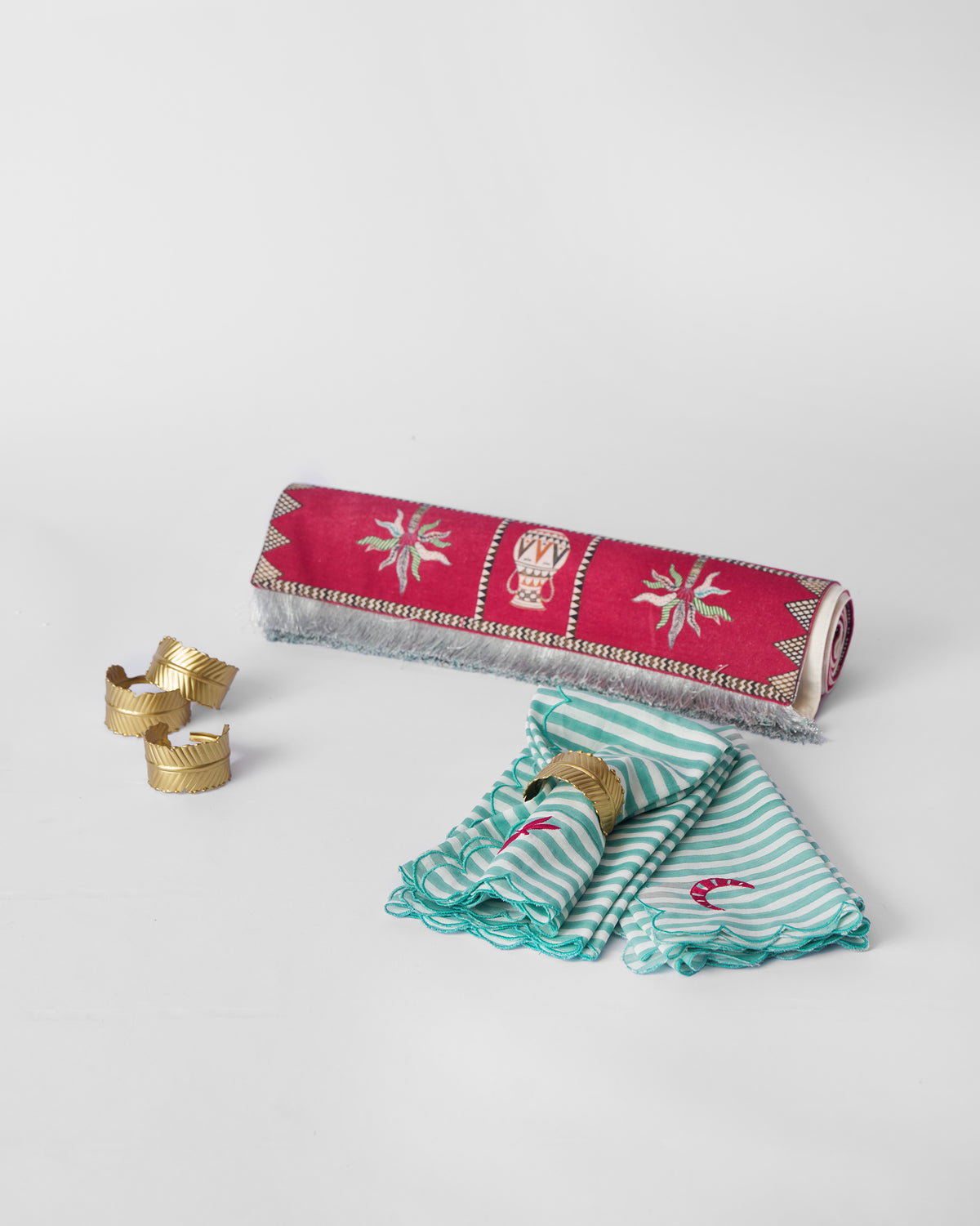 Harappa table runner, striped napkins and gold leaf napkin rings laid together.