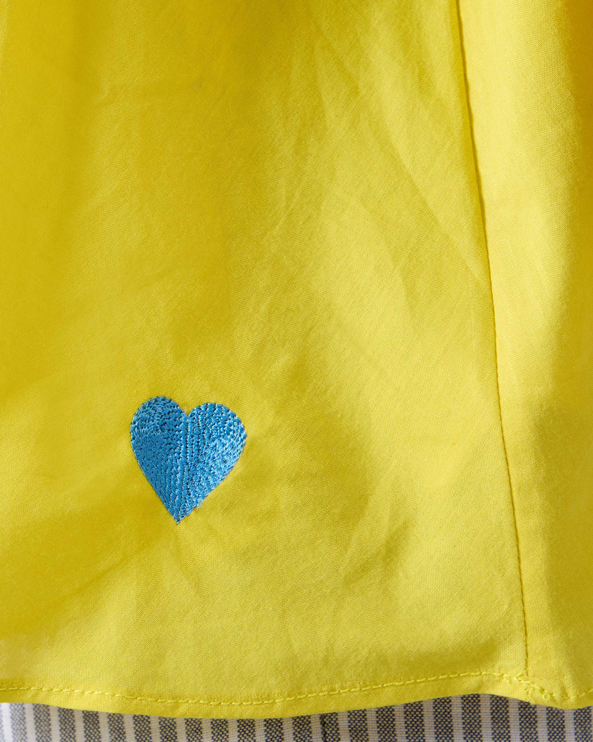 Close-up of a blue heart on a chartreuse Rann shirt.