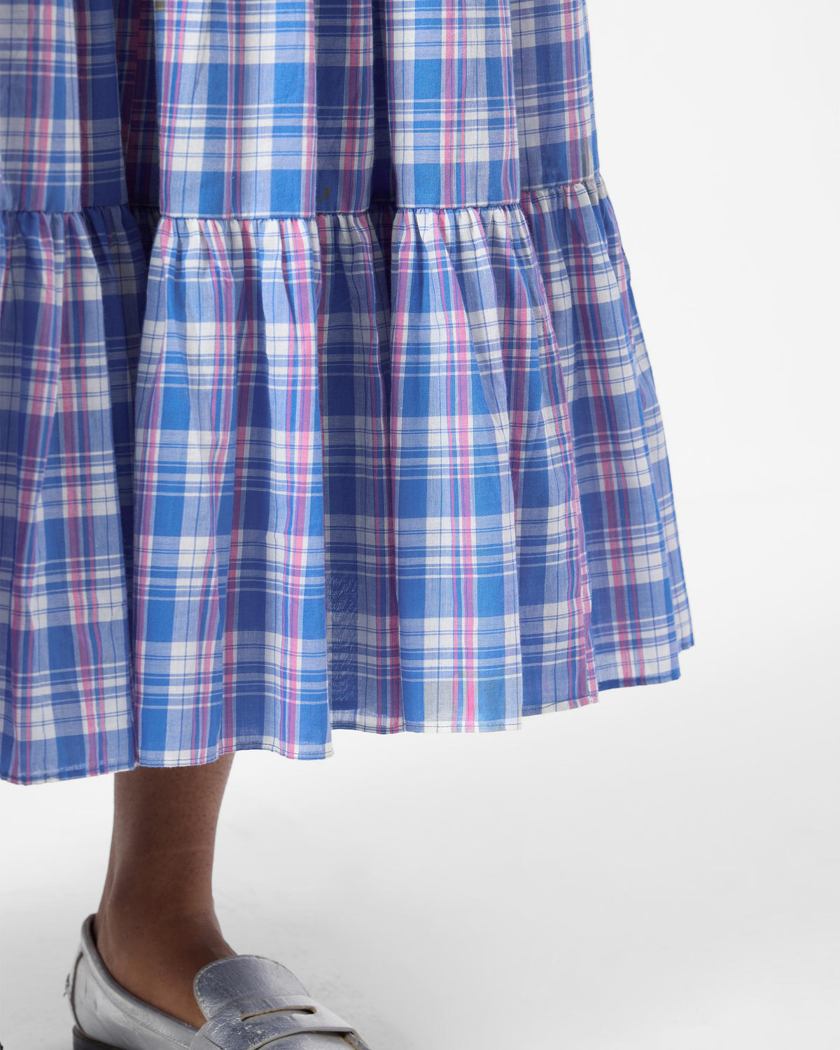 Close-up of the tiered hem on a blue checked Reah dress.
