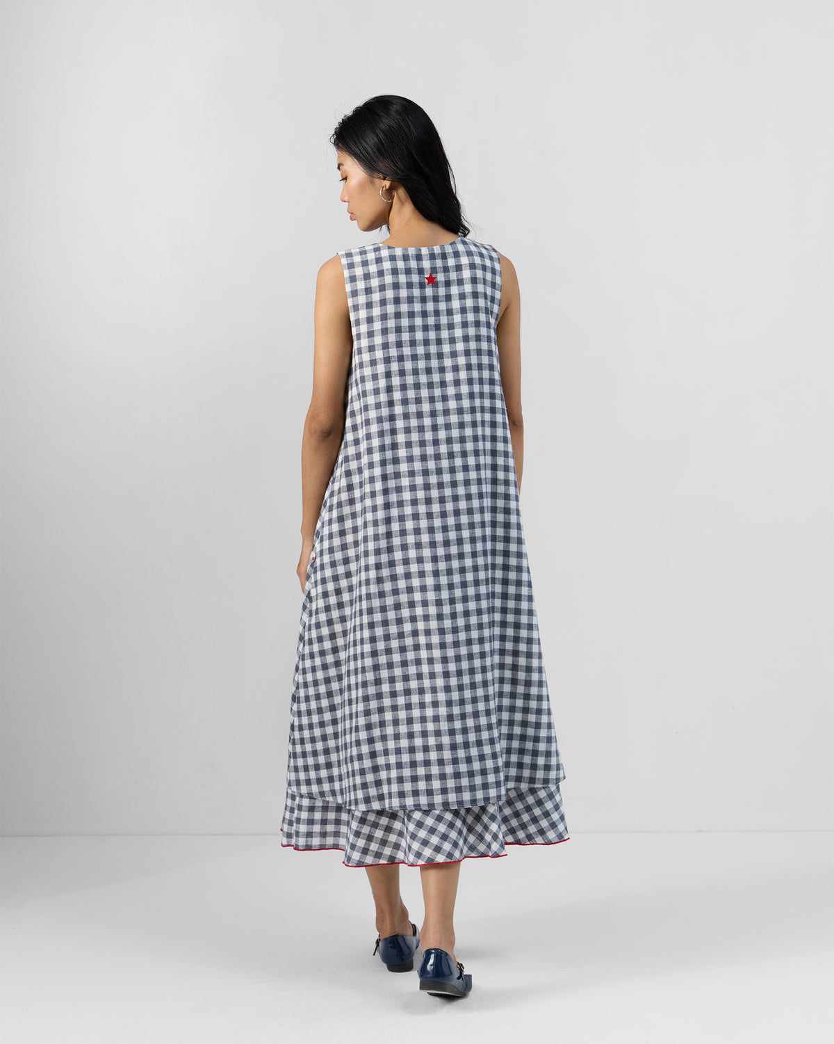 Back of a grey and white check Ezra dress with a red star embroidery.