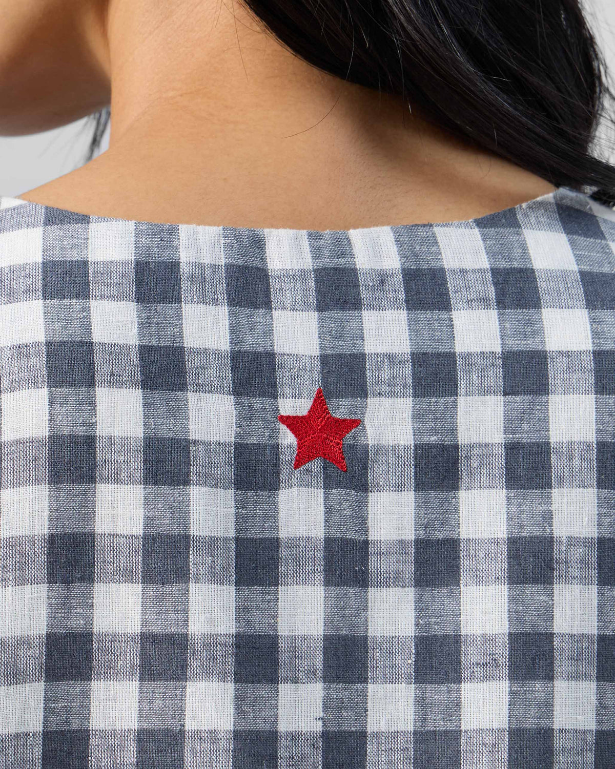 Close-up of a red star embroidery on a grey and white check Ezra dress.