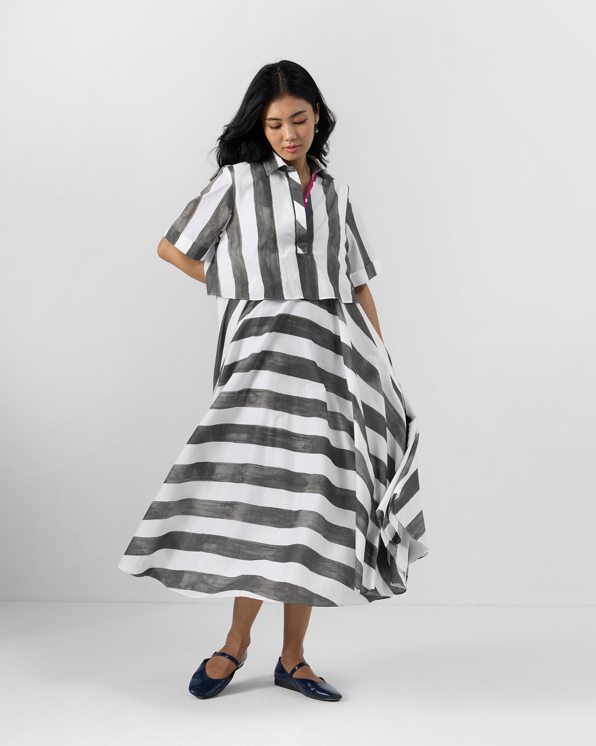 Person wearing a charcoal and white striped Kuro Dress with a flared midi skirt.