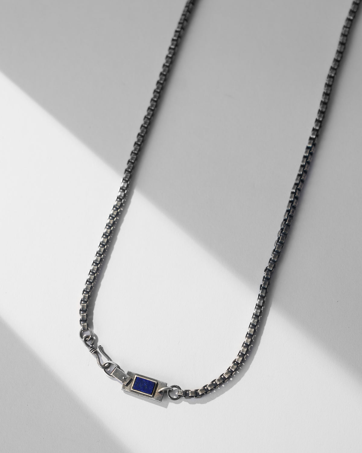 Close-up of silver Taro chain showing the rectangular lapis clasp.