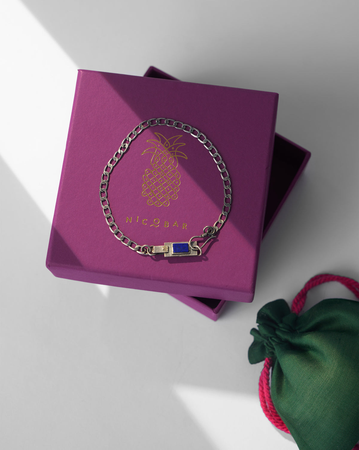 Silver Taro bracelet with a blue stone on a magenta Nicobar gift box.