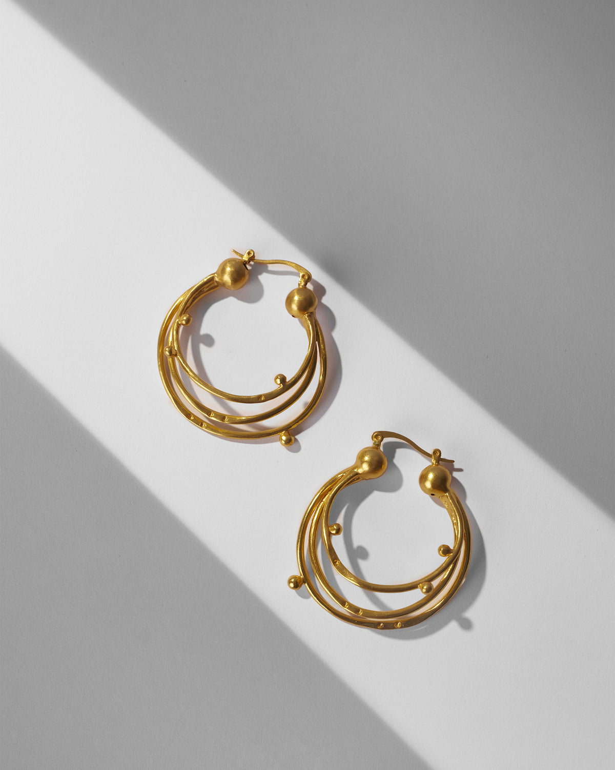 Pair of gold Celestial balis with triple nested hoops and bead accents.