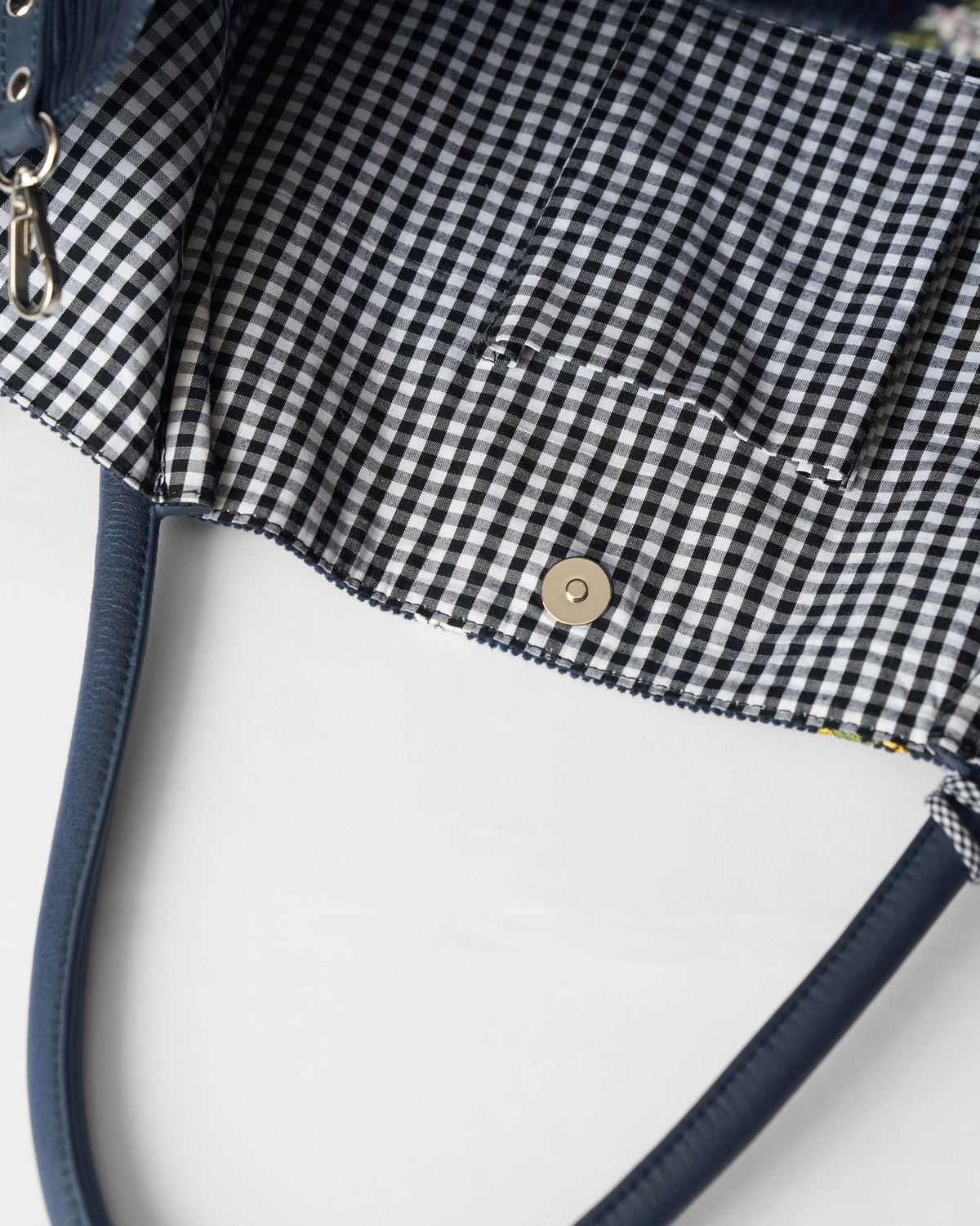 Interior of a navy Ditsy bag with gingham lining and a magnetic snap.