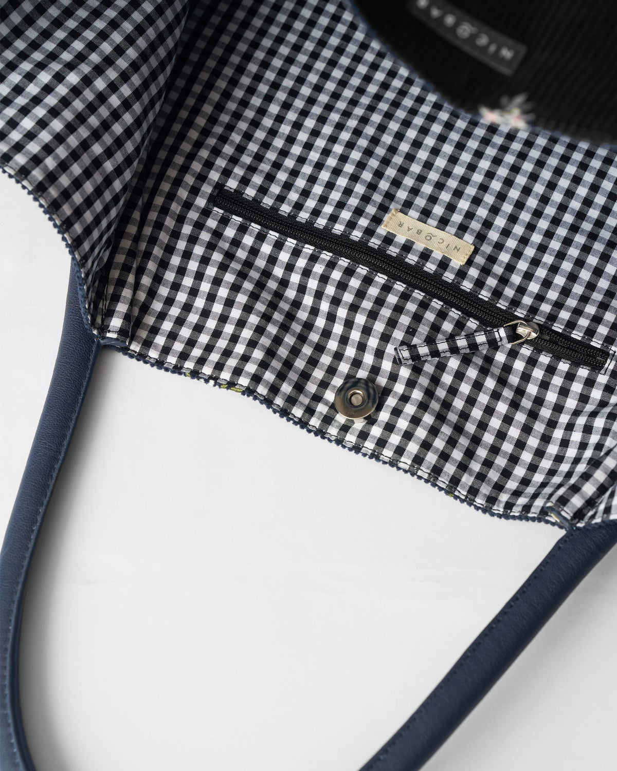 Interior zip pocket in the gingham lining of a navy Ditsy bag.