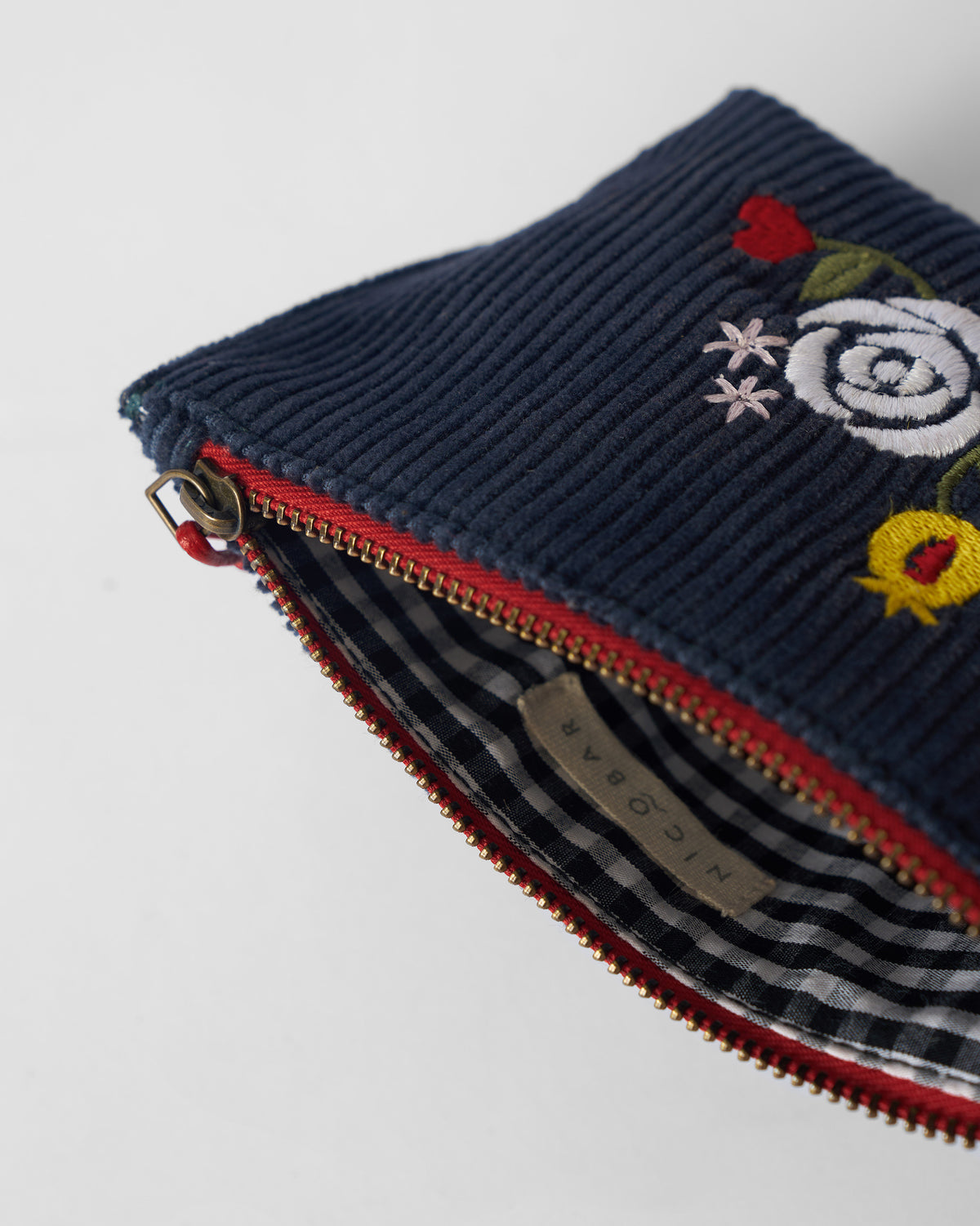 Close-up of the open navy Ditsy coin pouch with gingham lining.