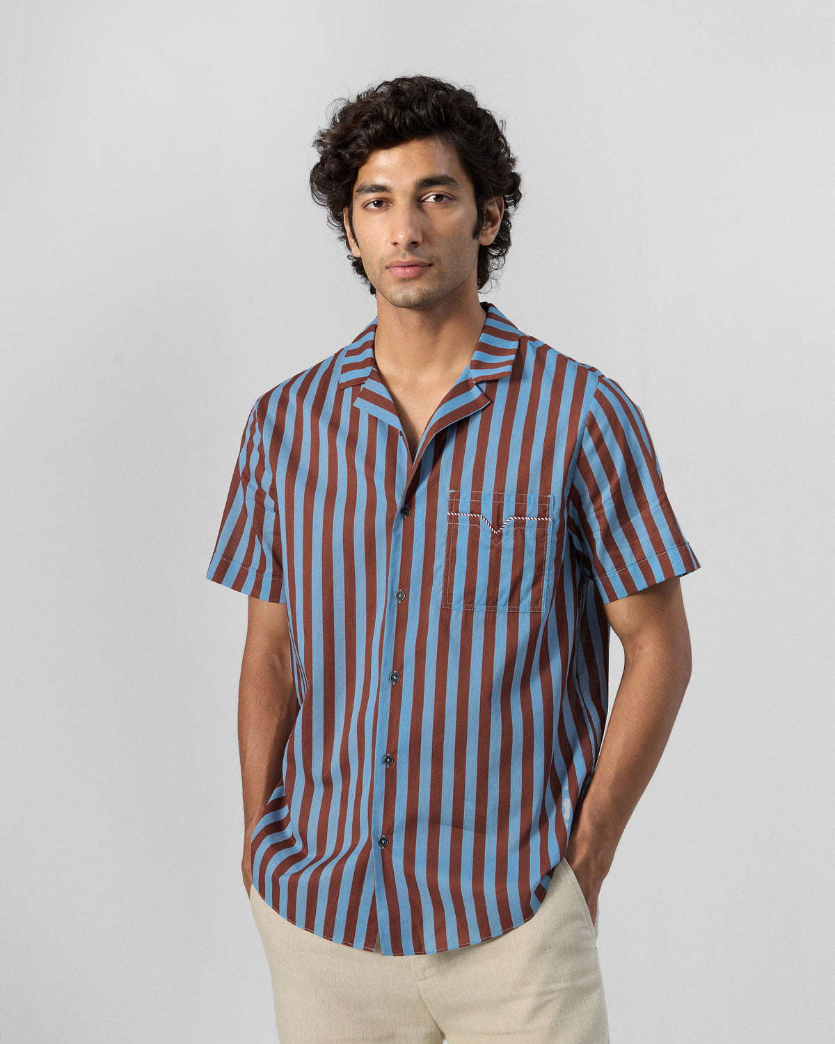 Person wearing a blue and brown striped Mason shirt with a notched chest pocket.