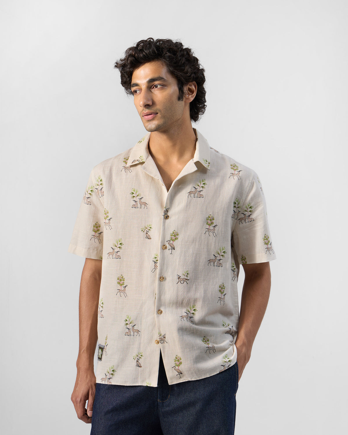Person wearing a cream Bena shirt with a deer and tree print.