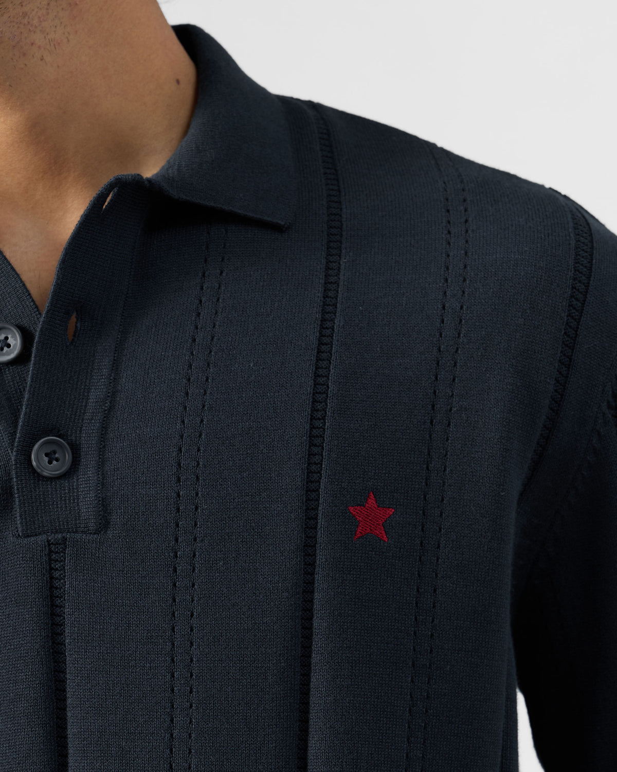 Close-up of a dark navy Midnight polo showing ribbed knit texture and a red star.