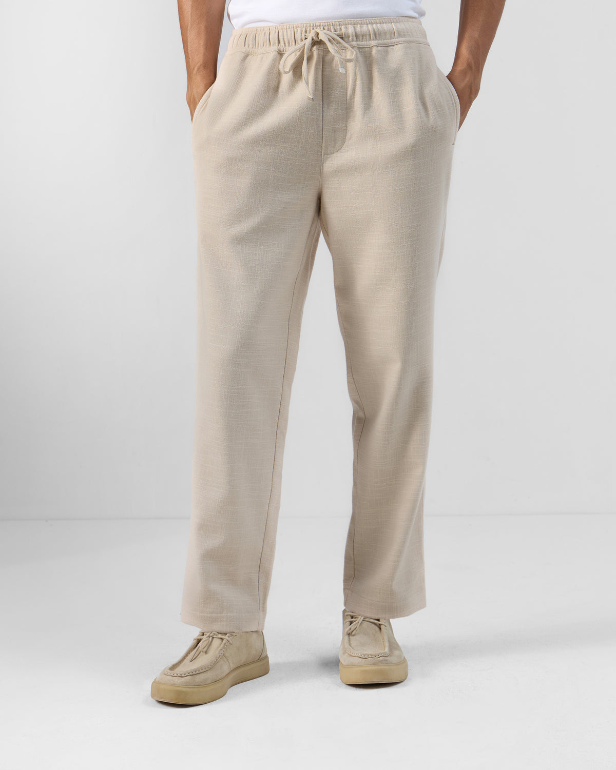 Person wearing beige Breeze trousers with a drawstring elastic waist.