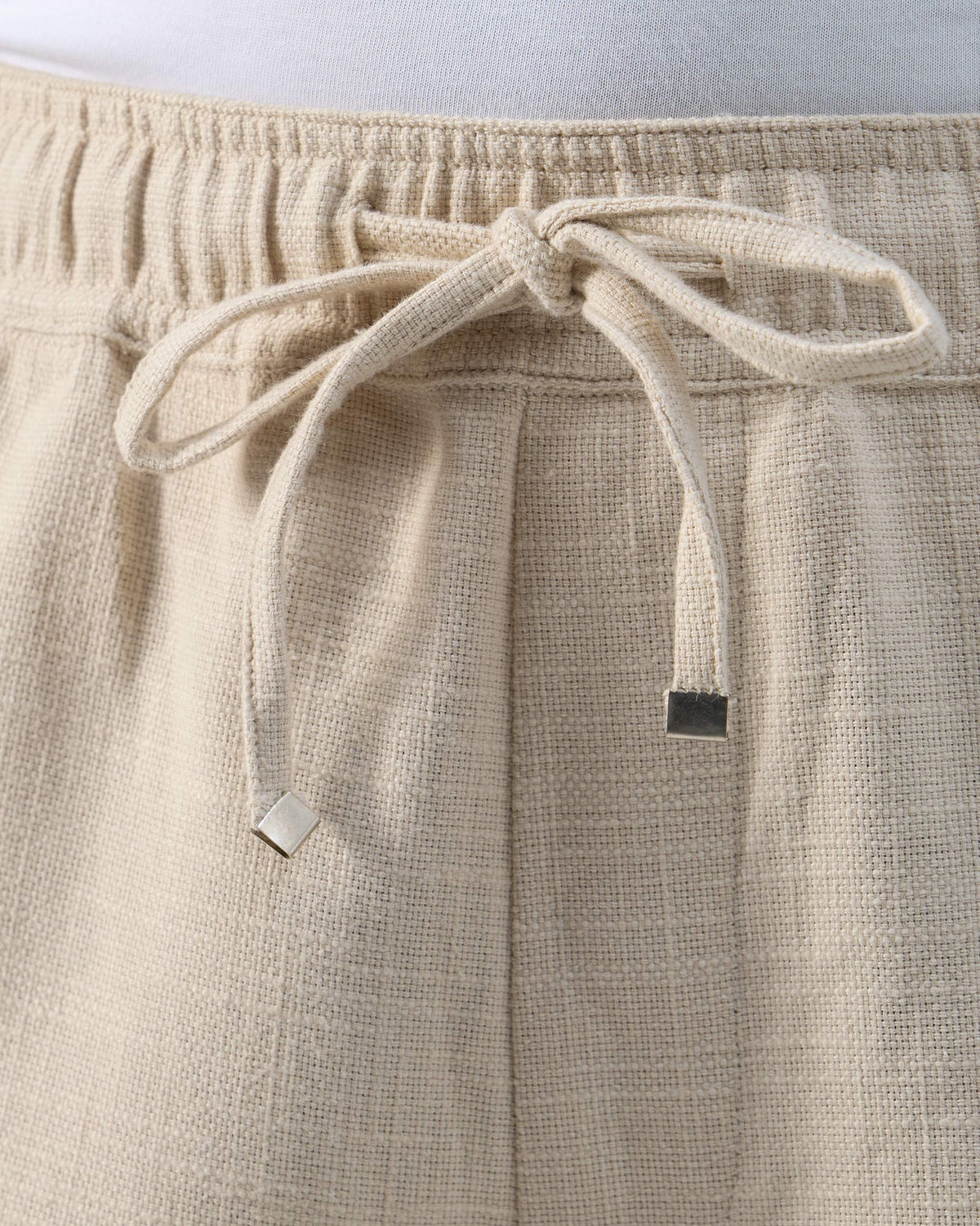 Close-up of the beige Breeze trouser drawstring with silver metal tips.