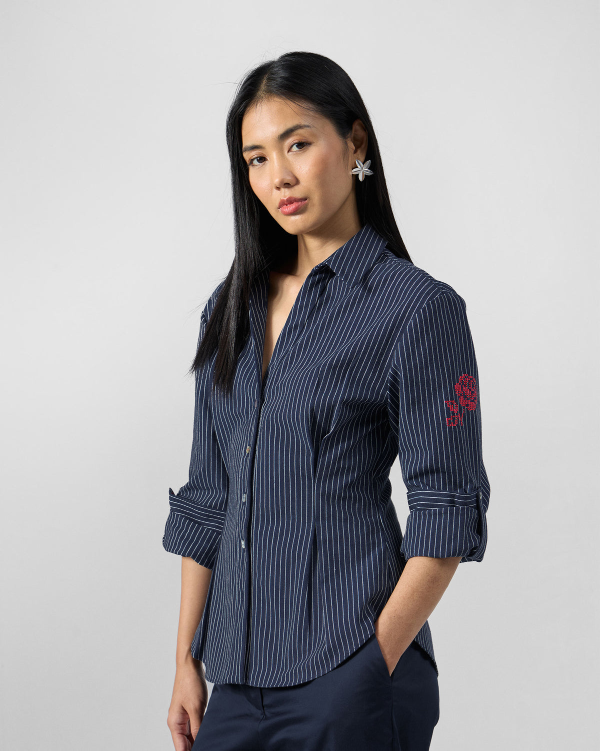 Person wearing a navy pinstripe Kalo shirt with a red rose on the sleeve.