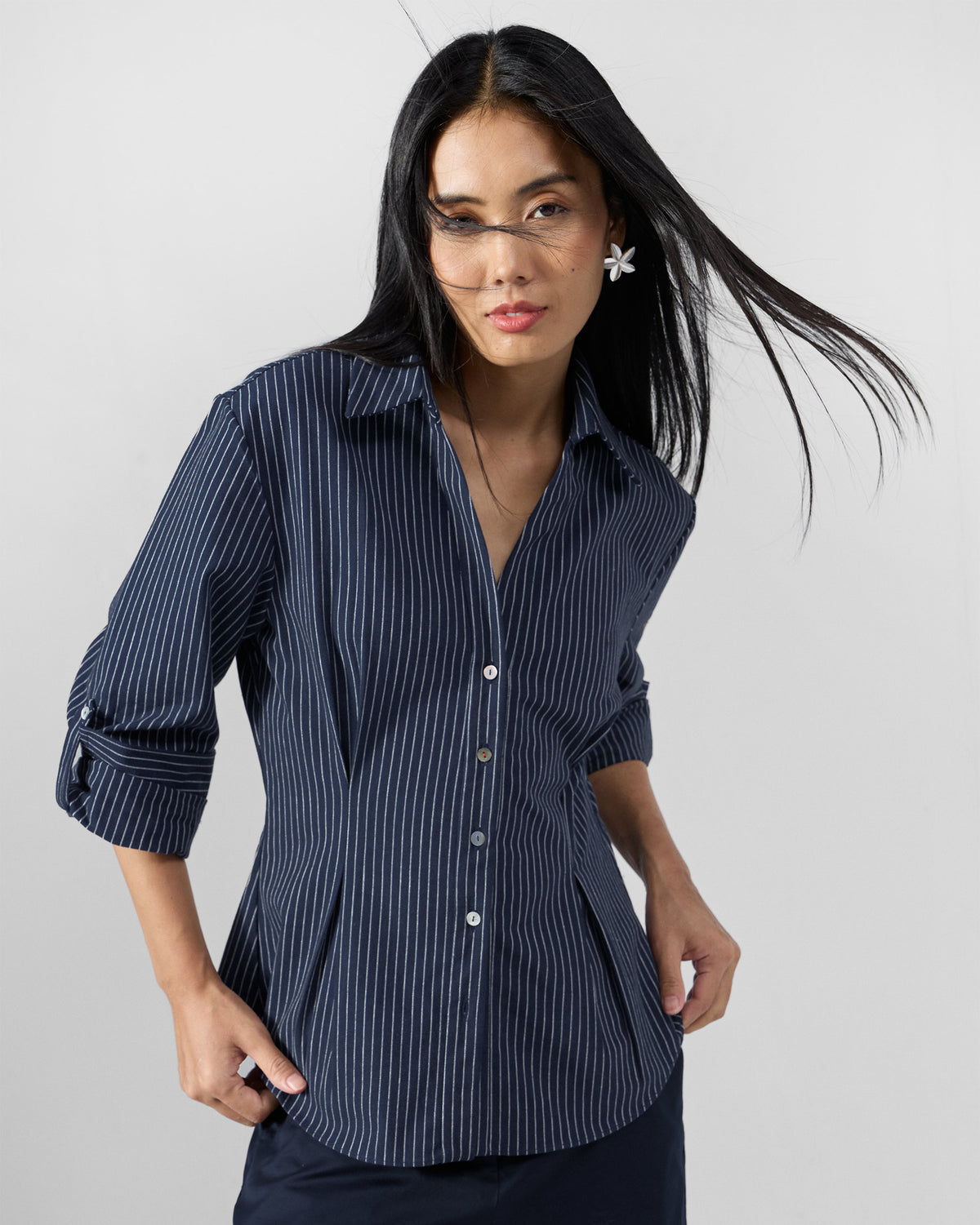 Front of a navy pinstripe Kalo shirt with waist darts and rolled sleeves.