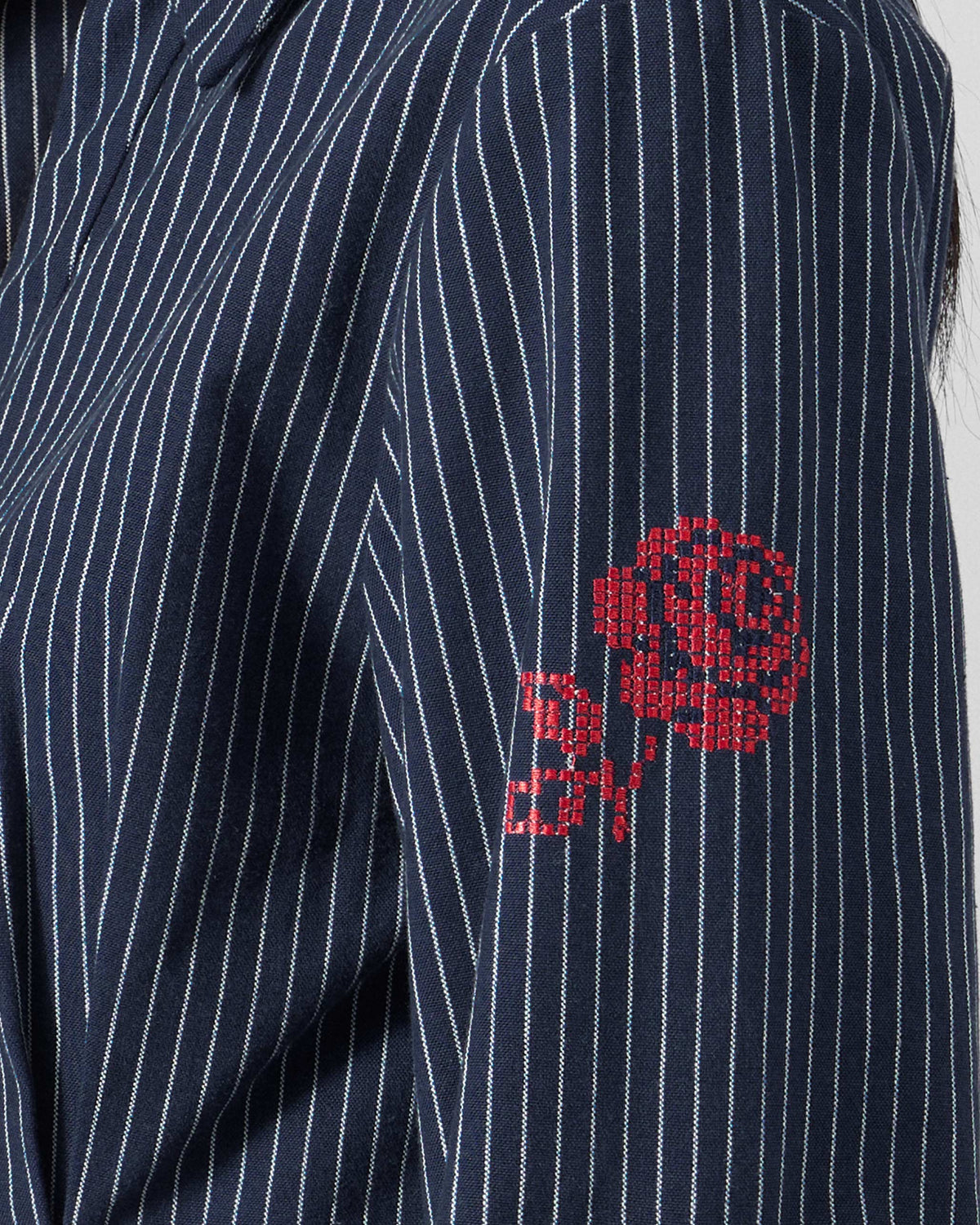 Close-up of a red embroidered rose on the navy pinstripe Kalo shirt sleeve.
