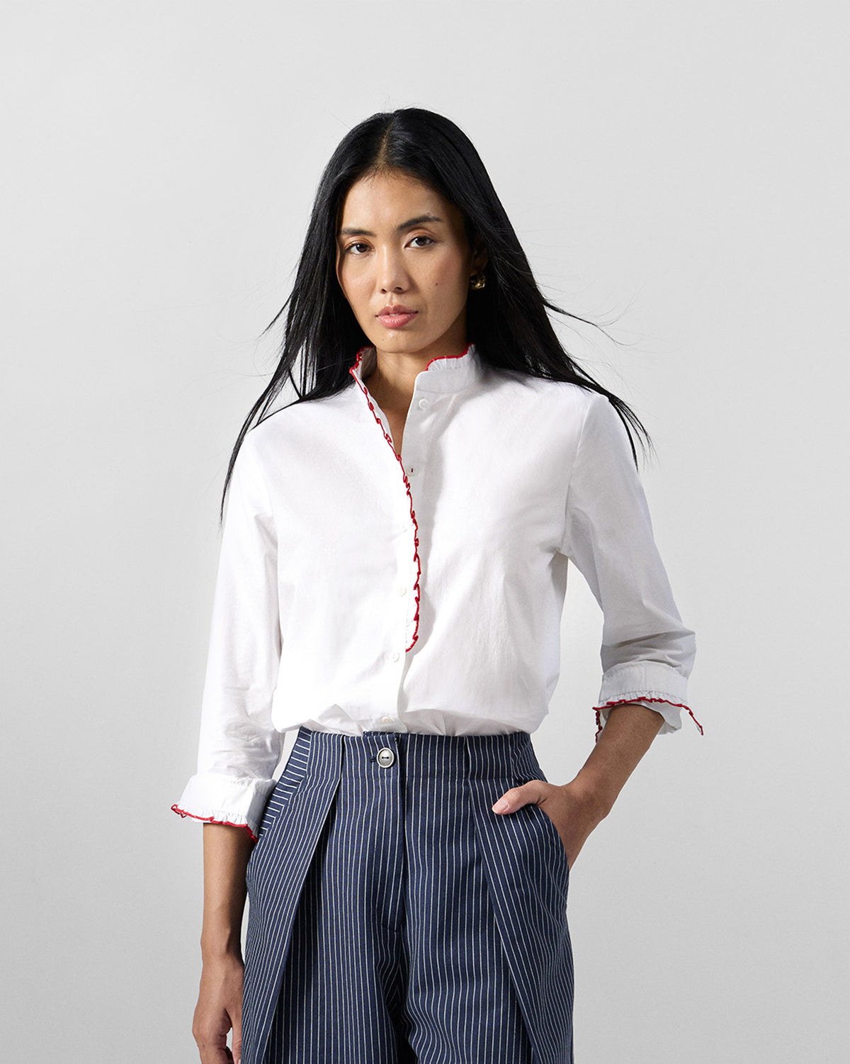 Person wearing a white Sora ruffle shirt with red trim.