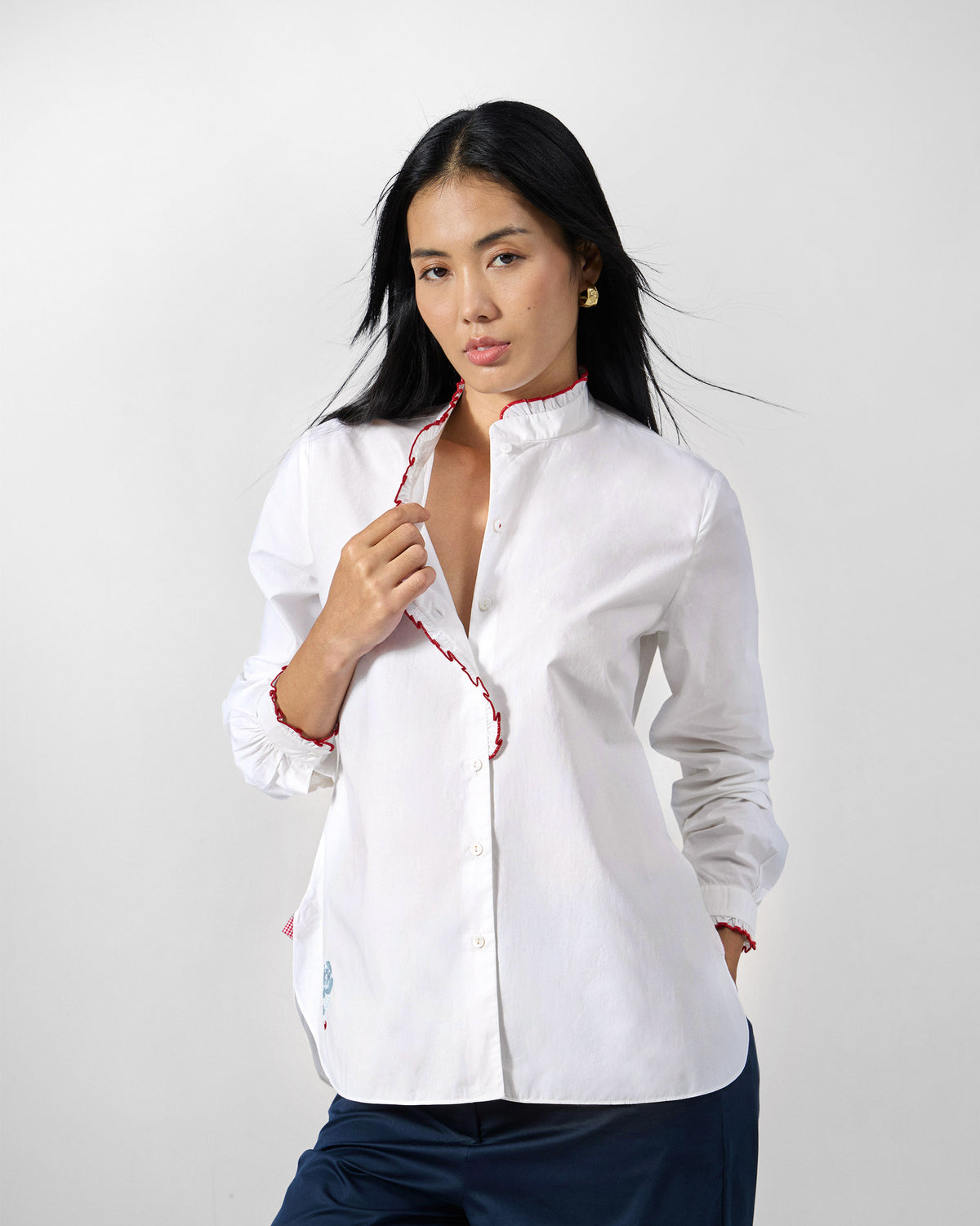 Person wearing a white Sora ruffle shirt with red trim.