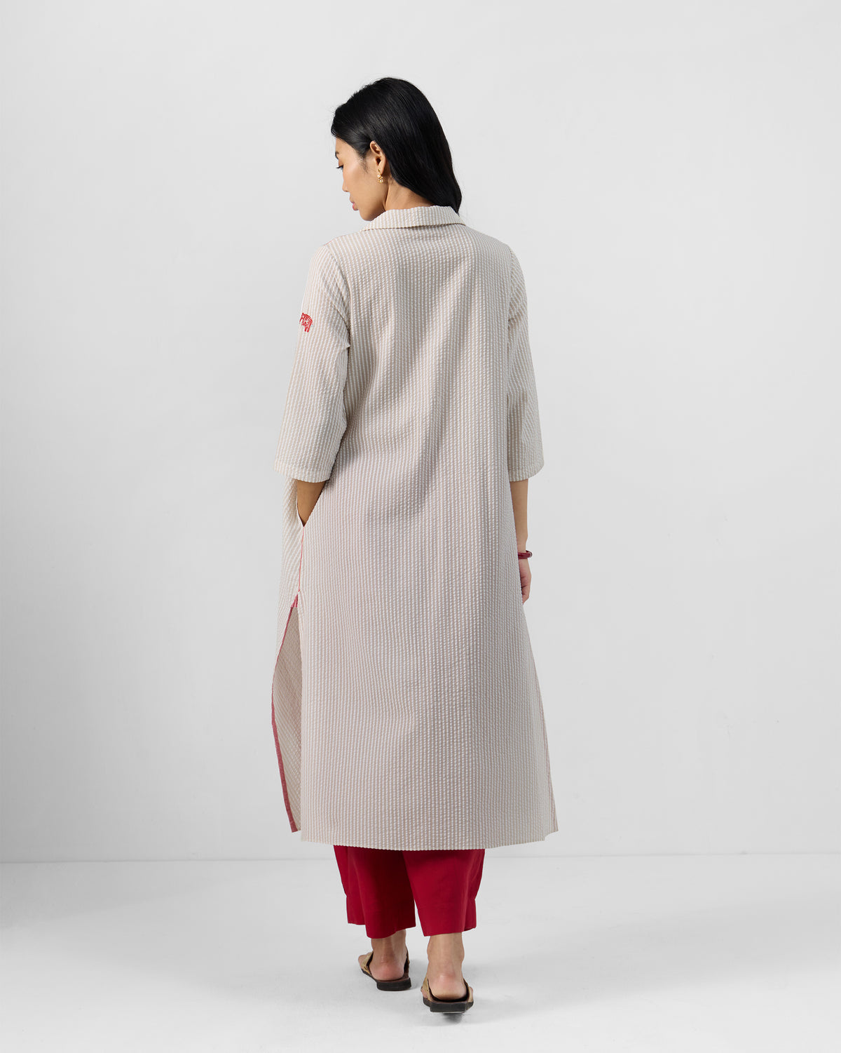 Back of an ivory-and-beige striped Maner seersucker kurta with deep side slits.