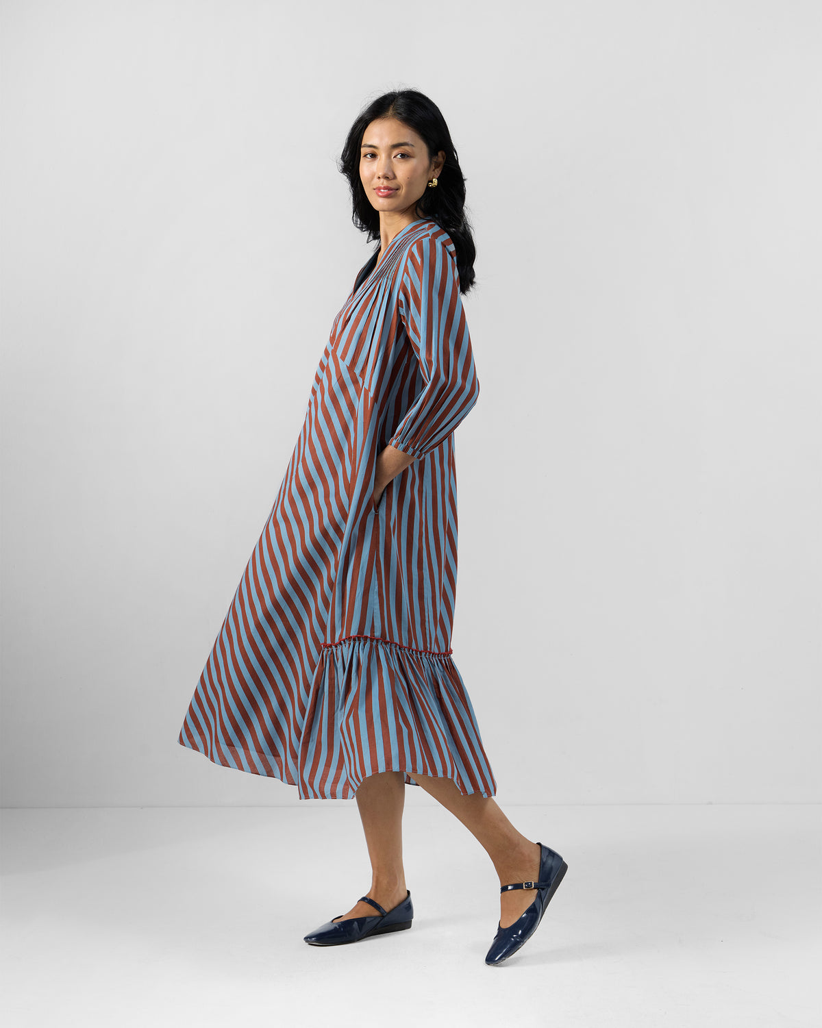 Side view of a blue and brown striped Summer Tea dress with pockets.