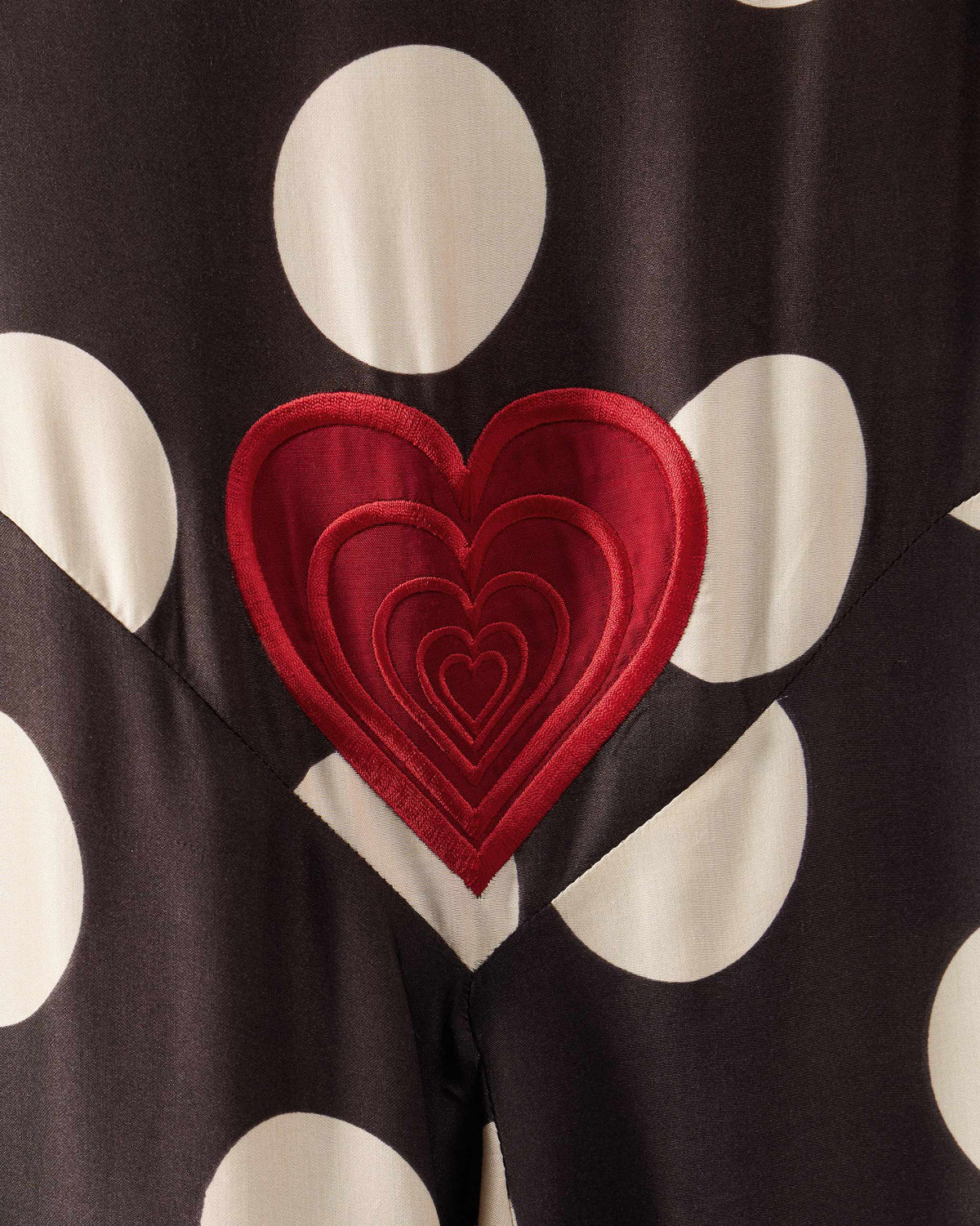 Close-up of a red nested heart embroidered on a brown polka-dot Kinaar Dress.