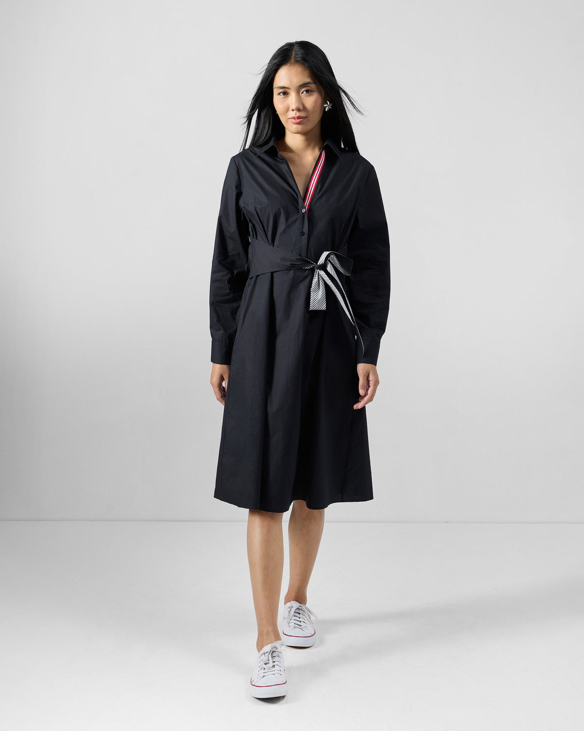 Person wearing a black shirt dress with a belted waist.