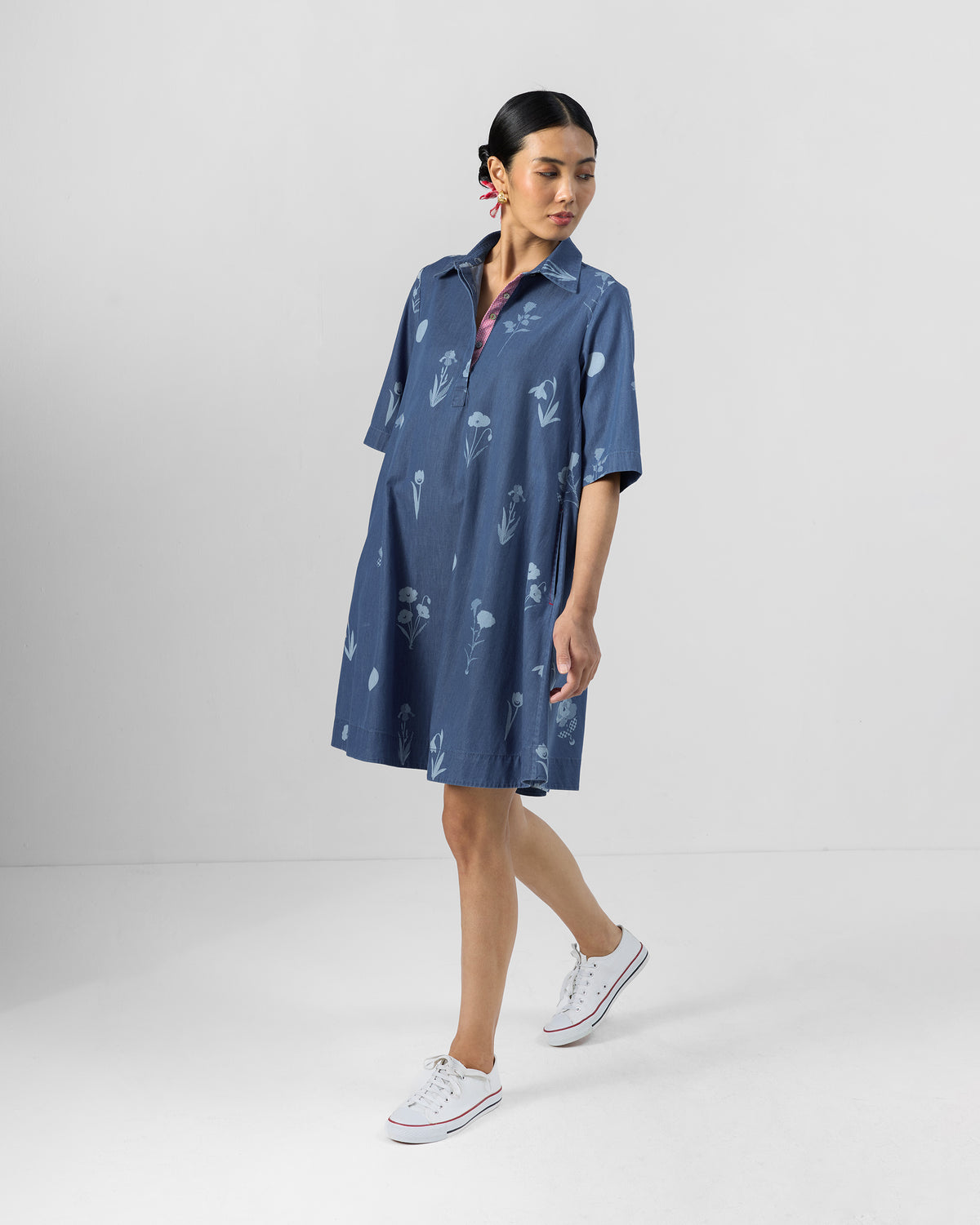 Person wearing a blue floral Happy Heart denim dress at knee length.