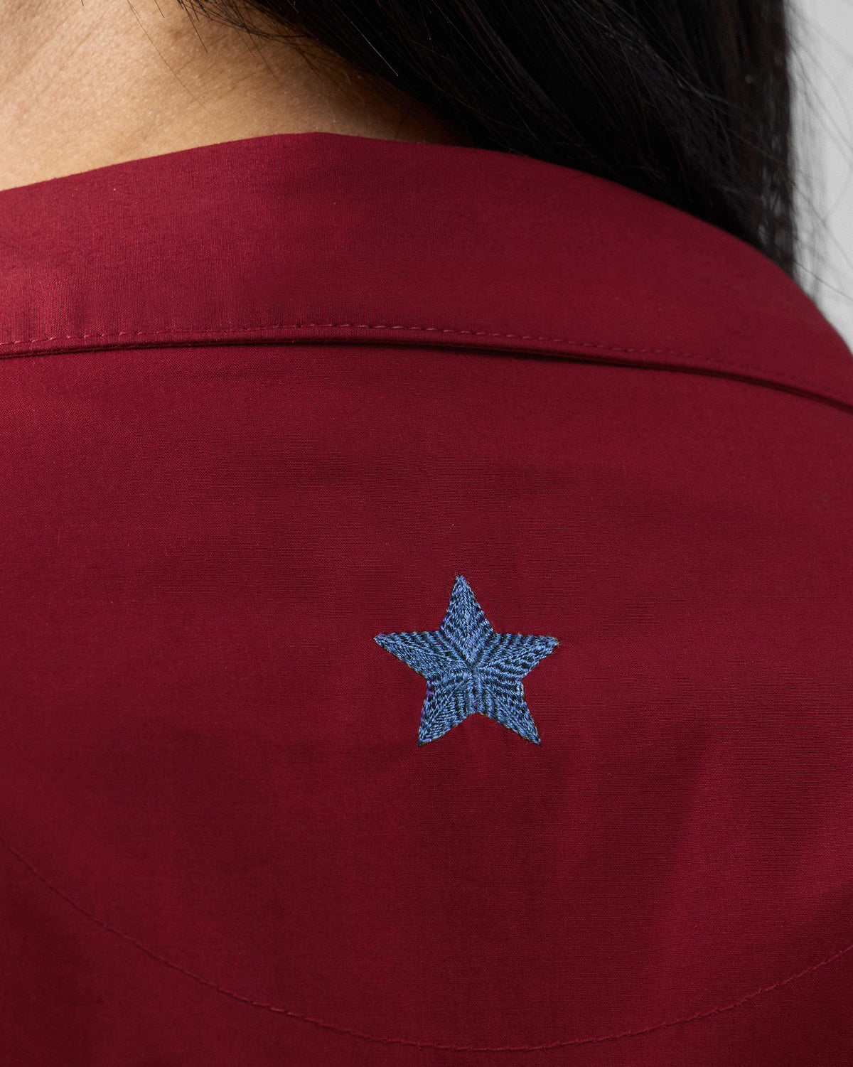 Close-up of a blue embroidered star on a red Nomad dress.