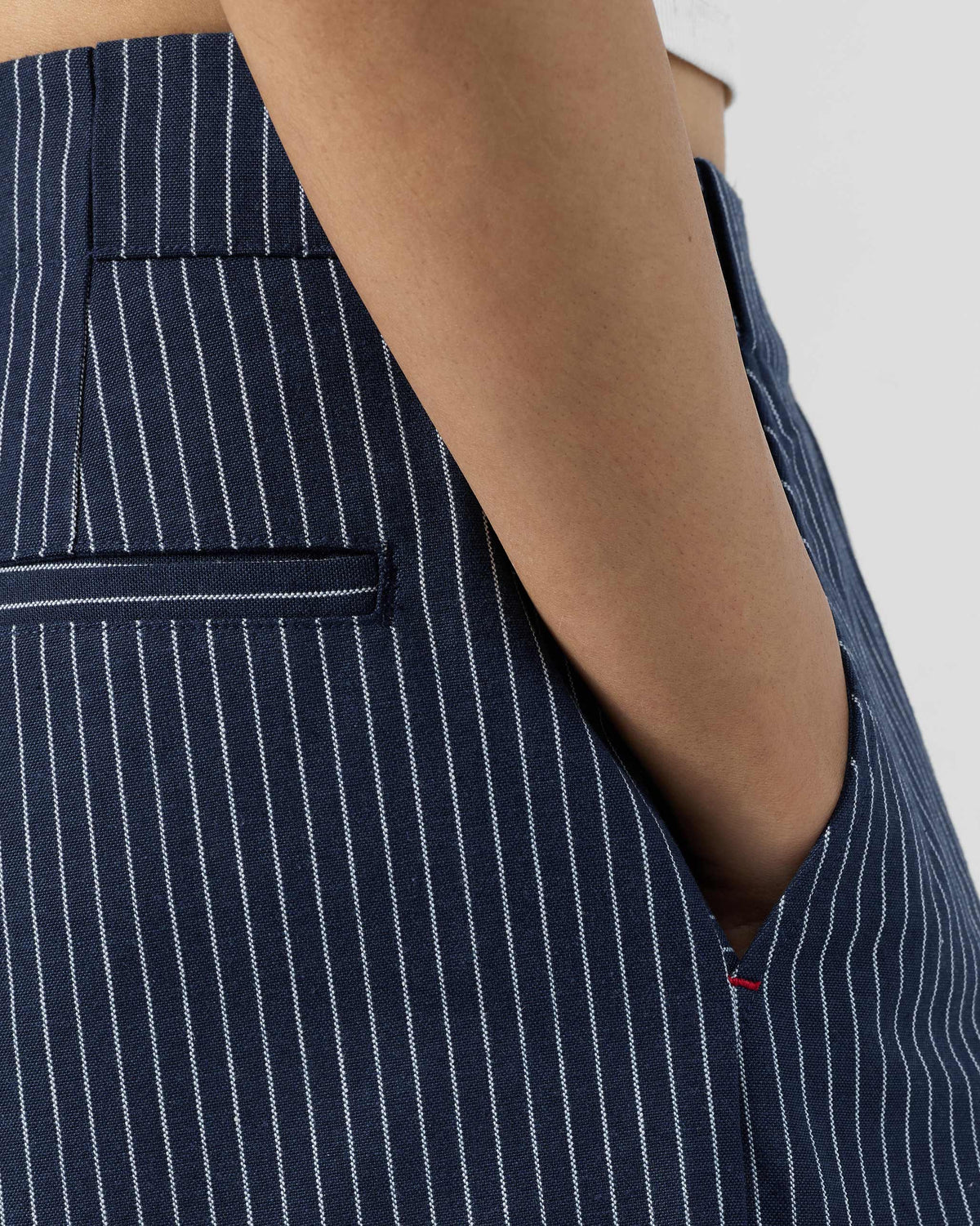 Close-up of navy striped Costa pants showing a side pocket with a red stitch.