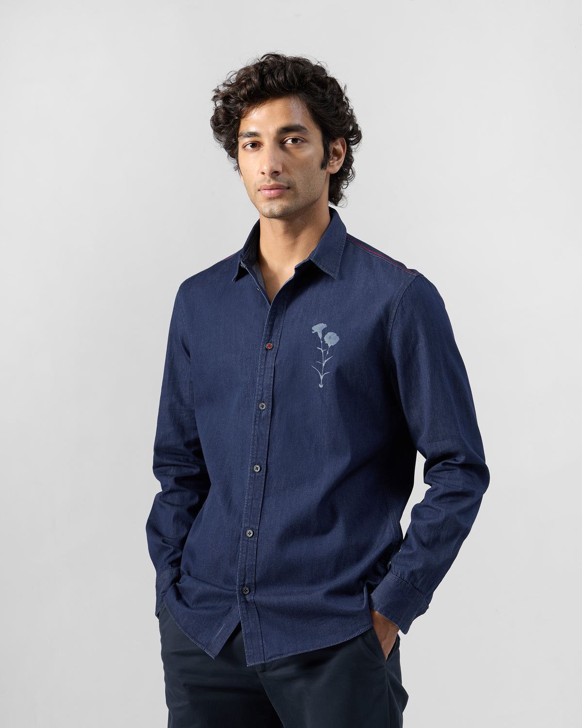 Person wearing an indigo denim Classic shirt with a floral chest print.