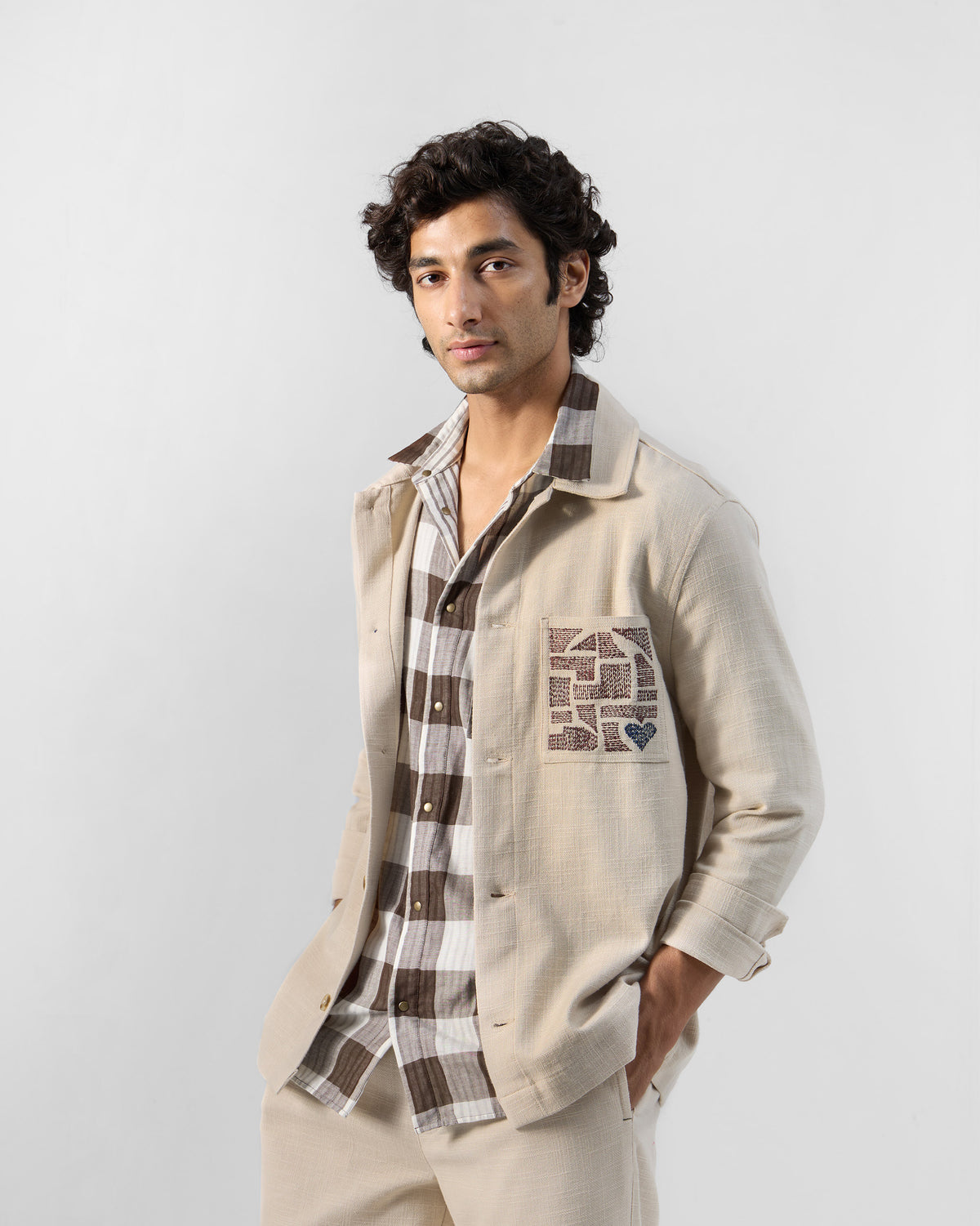 Person wearing a light beige Dune shacket with geometric pocket embroidery.